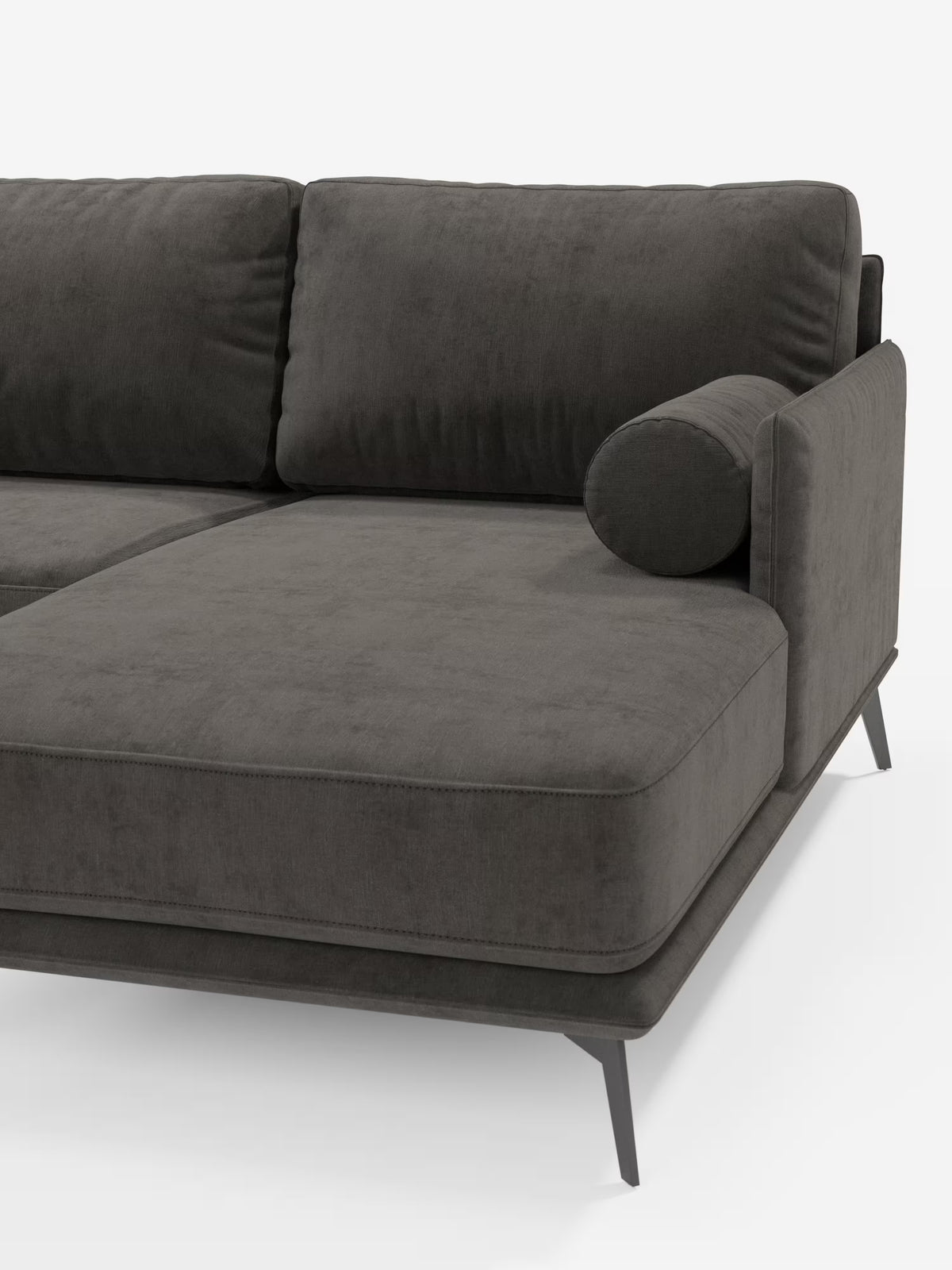 Il divano moderno angolare con penisola Basalto di Divani.Store è rivestito in tessuto T31 smacchiabile, di colore grigio antracite, morbido e vellutato, con soffici cuscini imbottiti in piuma, un cuscino cilindrico integrato nel bracciolo e una robusta base in metallo con eleganti gambe angolate. Questo divano componibile Made in Italy incarna un'eleganza raffinata ed è parzialmente visibile su uno sfondo bianco a tinta unita.