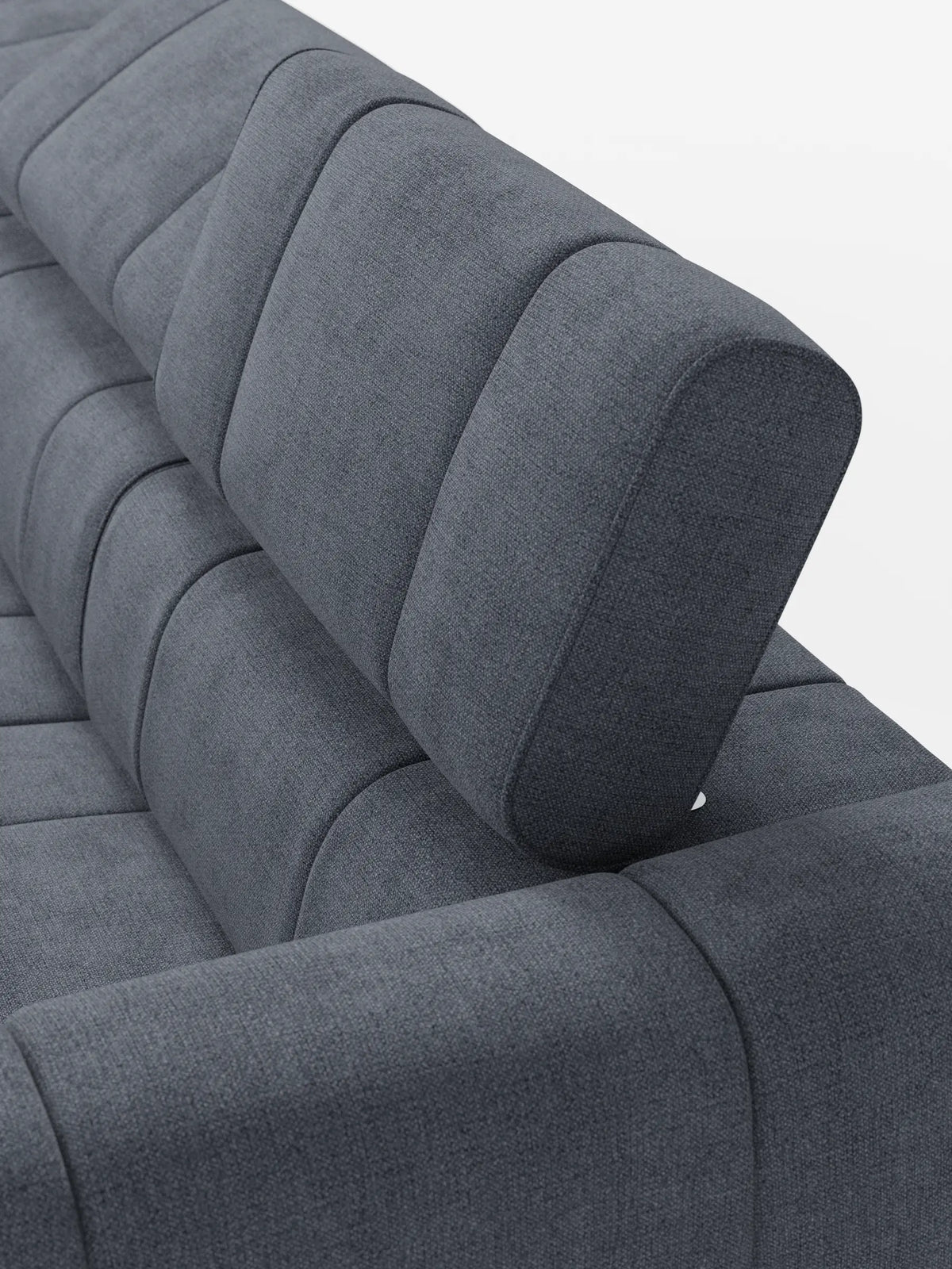 Un primo piano del divano modulare Giotto a 4 posti, color grigio scuro, con poggiatesta reclinabili e funzione relax elettrica opzionale, rivestito in tessuto smacchiabile T23, caratterizzato da una trapuntatura a canali verticali e da un poggiatesta regolabile su uno sfondo bianco a tinta unita.
