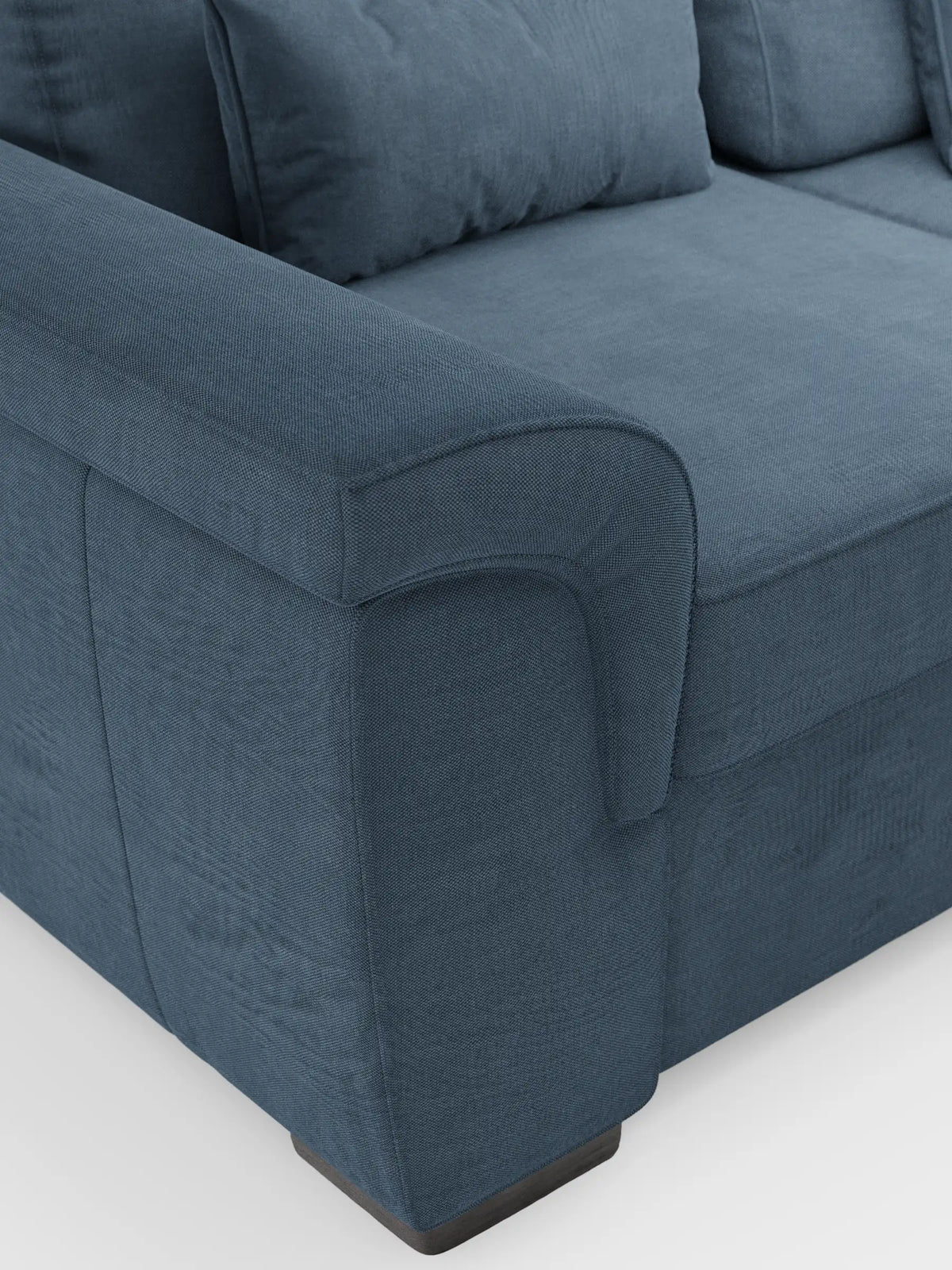 Un primo piano di un divano letto angolare blu “Ischia” con schienali scorrevoli, elemento estraibile e penisola contenitore in tessuto smacchiabile misto lino, caratterizzato da braccioli ricurvi, morbidi cuscini e piedini scuri su sfondo bianco.