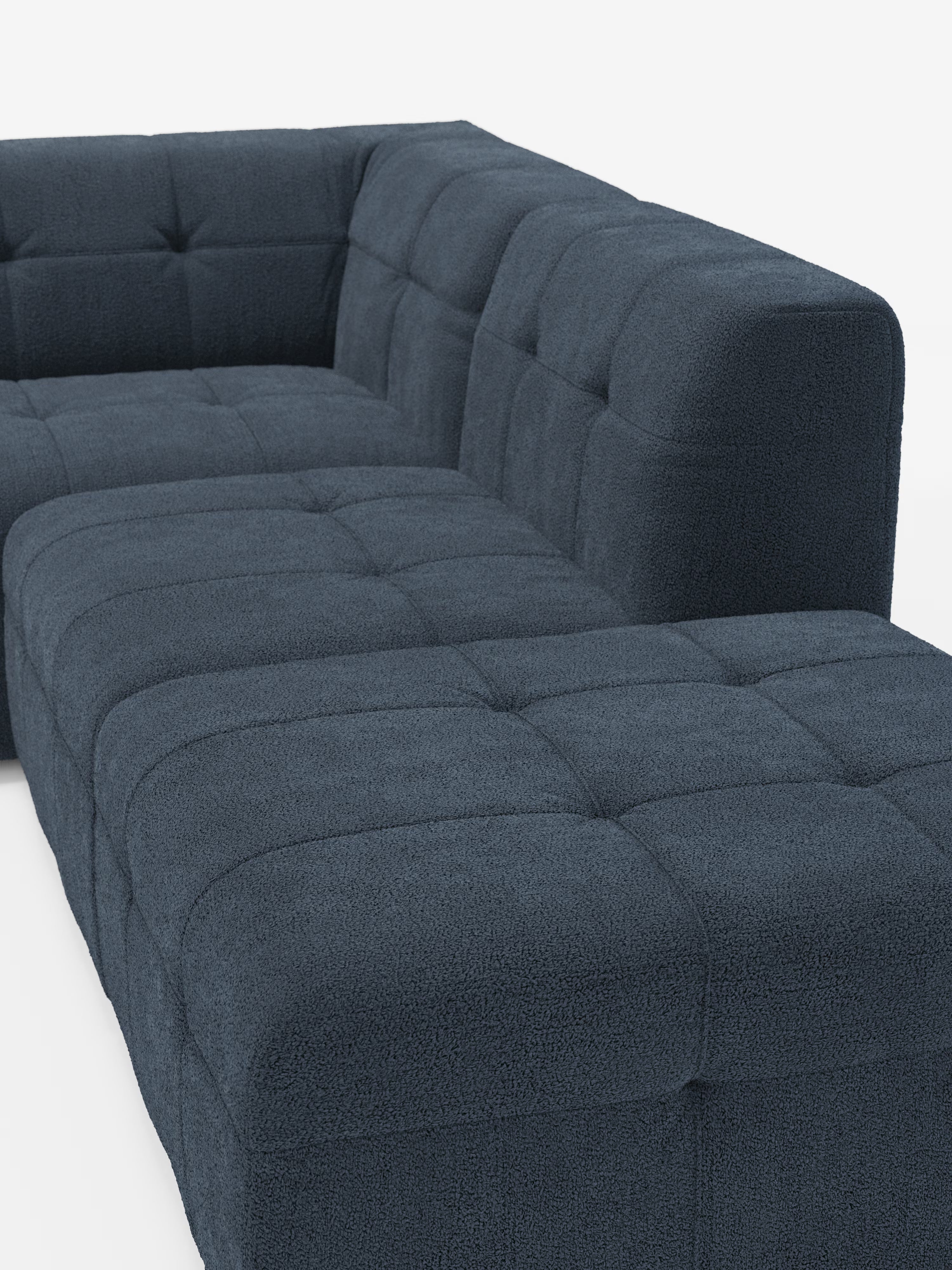 Un moderno divano angolare componibile e modulare Mosaic blu scuro in bouclé di Divani.Store, caratterizzato da un tessuto T21 morbido, strutturato e resistente alle macchie e da un motivo capitonné (imbottito) a griglia. Questo divano presenta cuscini spessi, una forma ad angolo retto e un design contemporaneo e minimalista. Il rivestimento in bouclé conferisce un tocco di eleganza e una piacevole sensazione al tatto sullo sfondo bianco a tinta unita.
