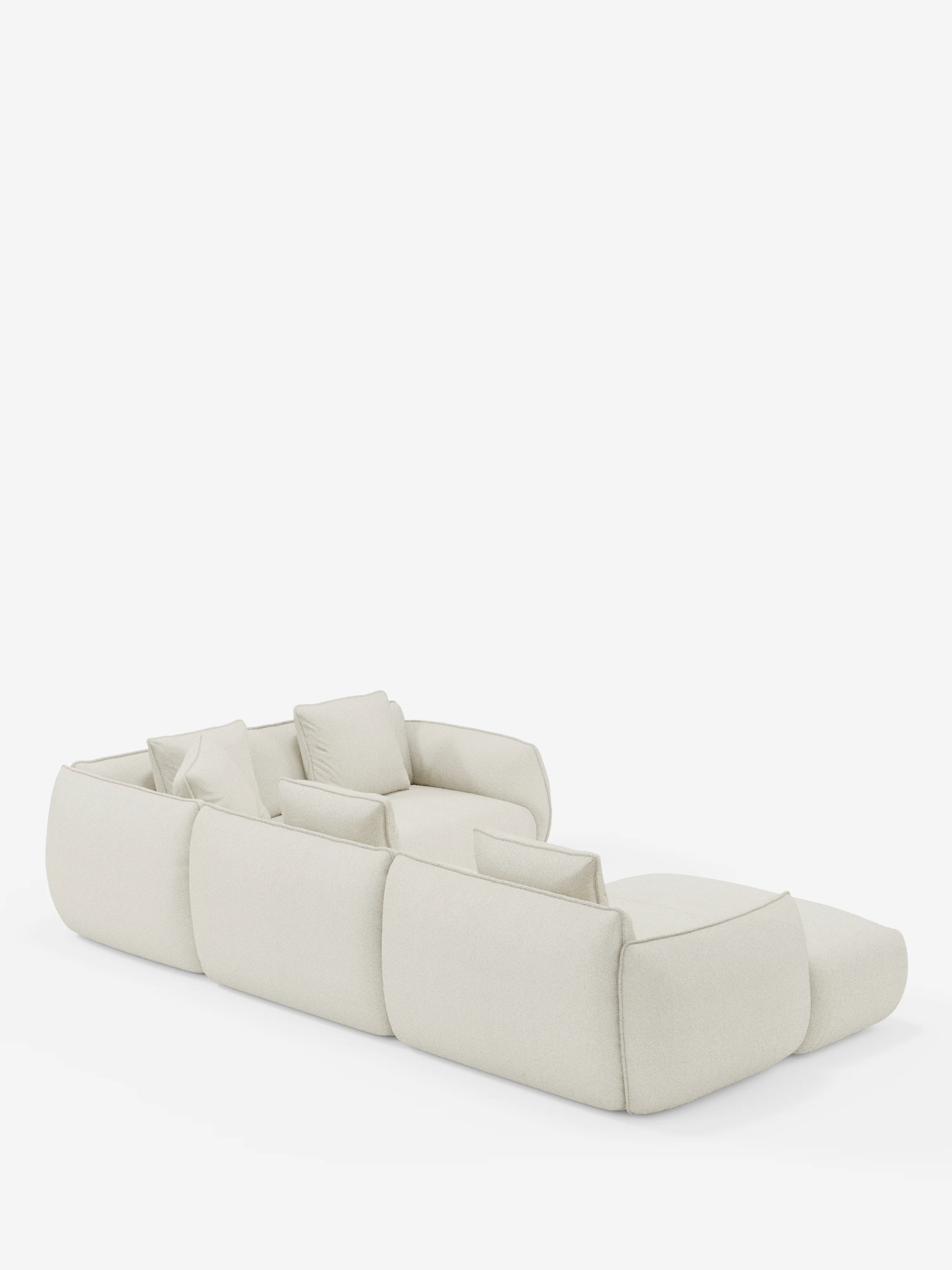 Un divano angolare panoramico modulare Nimbus, dal profilo basso e color beige, con penisola e angolo in tessuto smacchiabile T33 di Divani.Store, Made in Italy, caratterizzato da tre ampie sezioni di seduta e cinque cuscini quadrati coordinati. Ritratto da un'angolazione posteriore su uno sfondo bianco a tinta unita, il suo design morbido e arrotondato conferisce a questo divano modulare un aspetto rilassato e contemporaneo.
