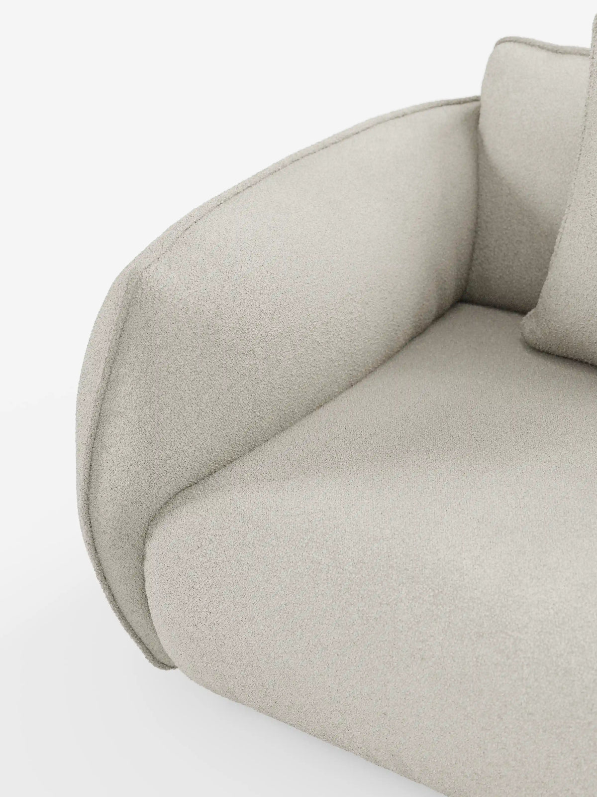 Primo piano di un moderno divano Nimbus a 3 posti, modulare e componibile, di Divani.Store, rivestito in tessuto T33 beige chiaro, testurizzato e smacchiabile, effetto cotone. I braccioli e lo schienale si snodano in curve morbide, conferendo al divano un aspetto soffice e arrotondato. Un cuscino coordinato è parzialmente visibile su uno sfondo bianco a tinta unita.