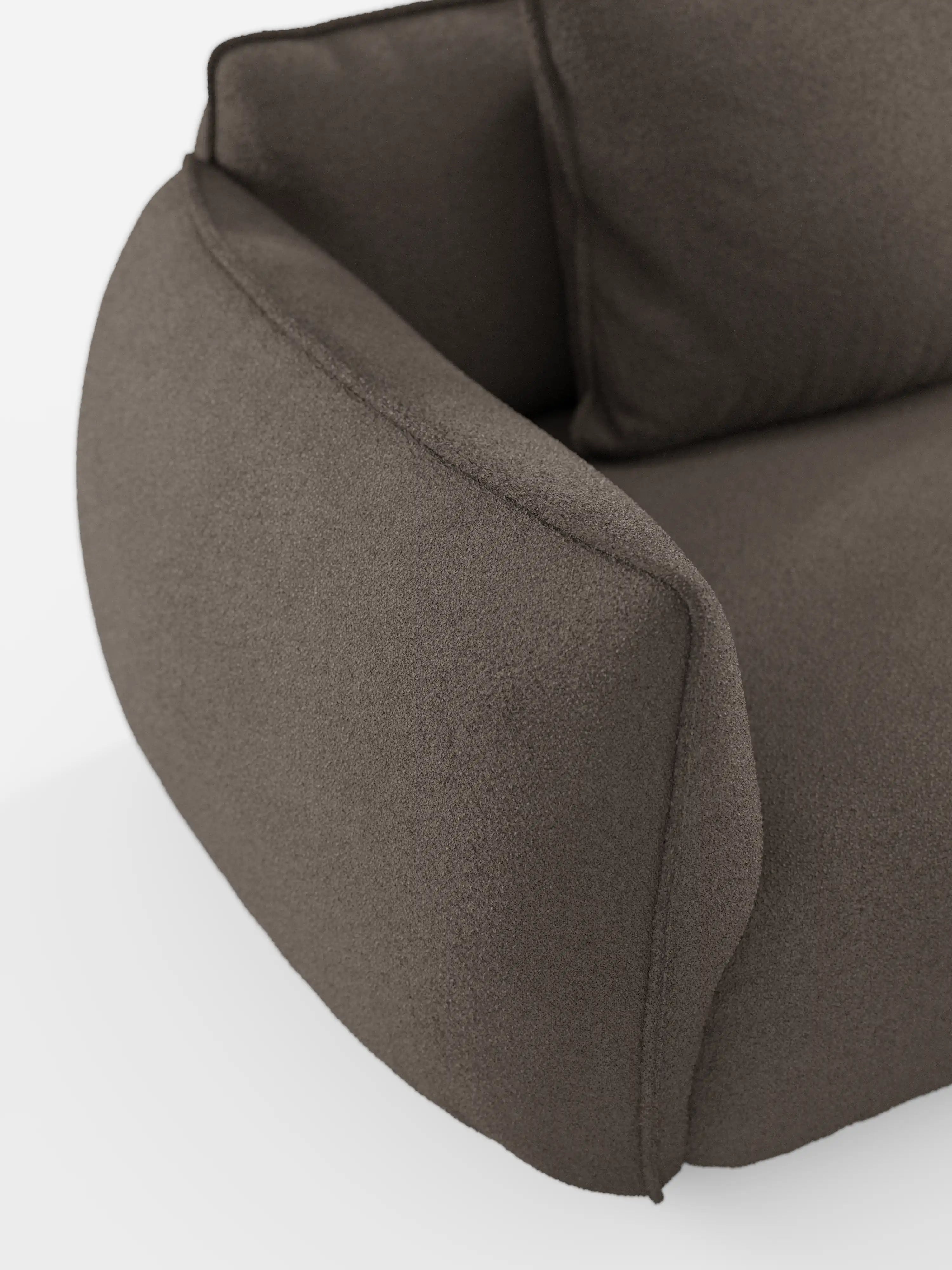 Primo piano di un moderno divano angolare con penisola componibile Nimbus, color grigio scuro, di Divani.Store, che mette in risalto il morbido tessuto T33 effetto cotone e resistente alle macchie. Il bracciolo presenta un design arrotondato e massiccio e un cuscino soffice, mentre lo sfondo bianco a tinta unita esalta lo stile contemporaneo e la texture accogliente di questo divano componibile.