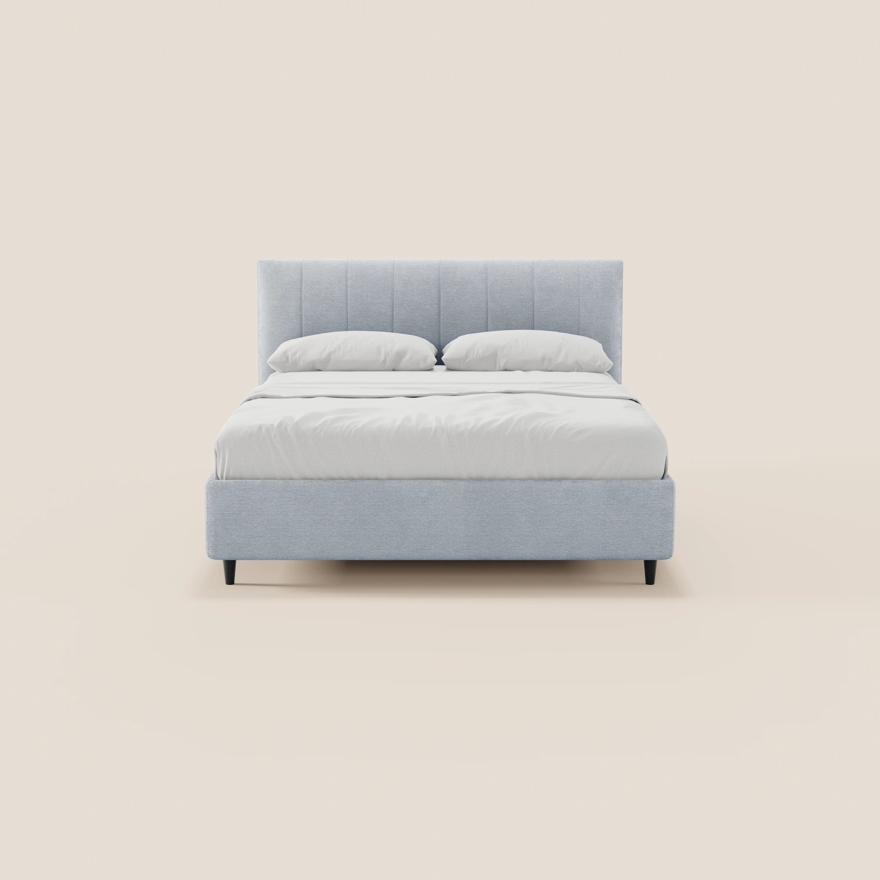 Il letto imbottito ONYX con contenitore e testiera verticale in tessuto Oeko-Tex® di Letti.store, con testiera e struttura imbottite in grigio chiaro, biancheria da letto bianca e due cuscini, poggia su corte gambe in legno scuro su uno sfondo beige.
