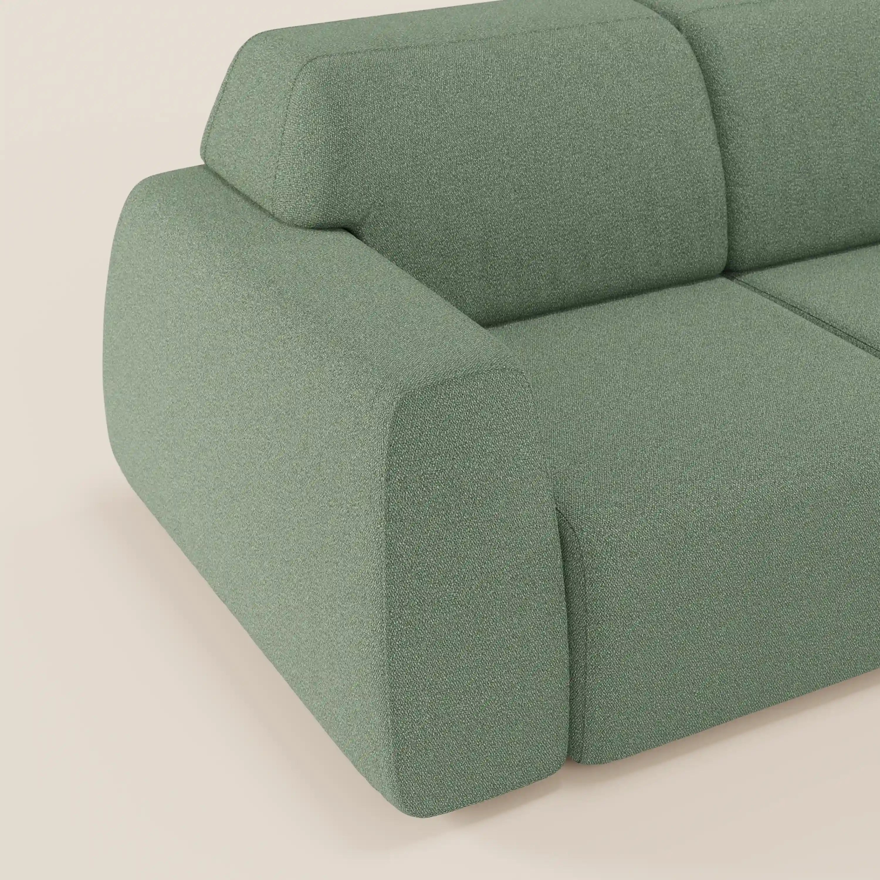 Primo piano di Orbit divano con 3 sedute scorrevoli e allungabili di Divani.Store, in tessuto effetto cotone verde salvia, facile da pulire, con bordi morbidi e arrotondati e braccioli in feltro: un comfort perfetto su uno sfondo neutro.