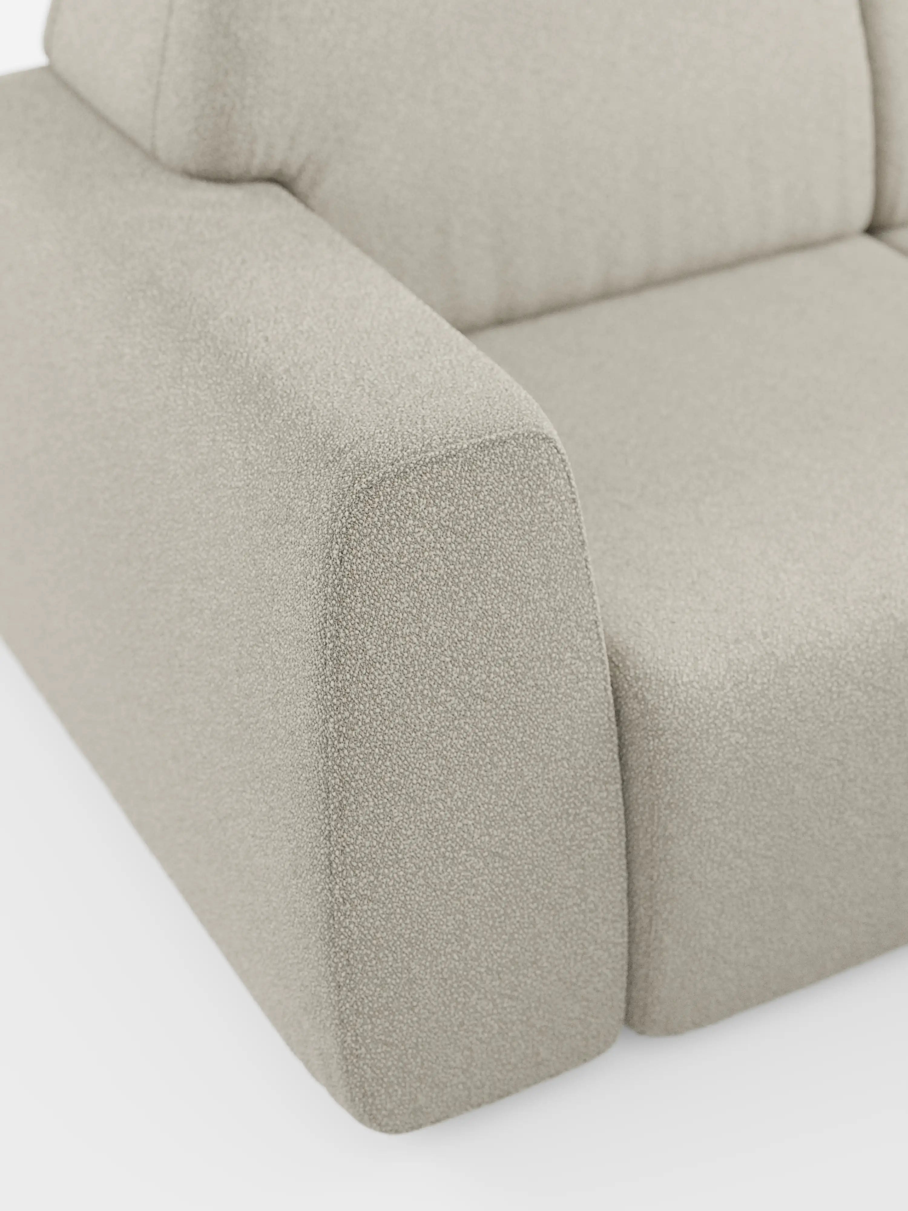 Un primo piano del divano angolare Orbit con penisola reversibile e tutte le sedute allungabili in tessuto smacchiabile effetto cotone T33 di Divani.Store, con particolare attenzione al bracciolo sinistro, alla seduta e allo schienale. Il tessuto beige chiaro presenta una finitura testurizzata e ben tesa, con linee pulite e un'imbottitura morbida. Progettato per garantire versatilità e comfort, lo stile minimalista di questo divano modulare è esaltato dallo sfondo bianco a tinta unita.