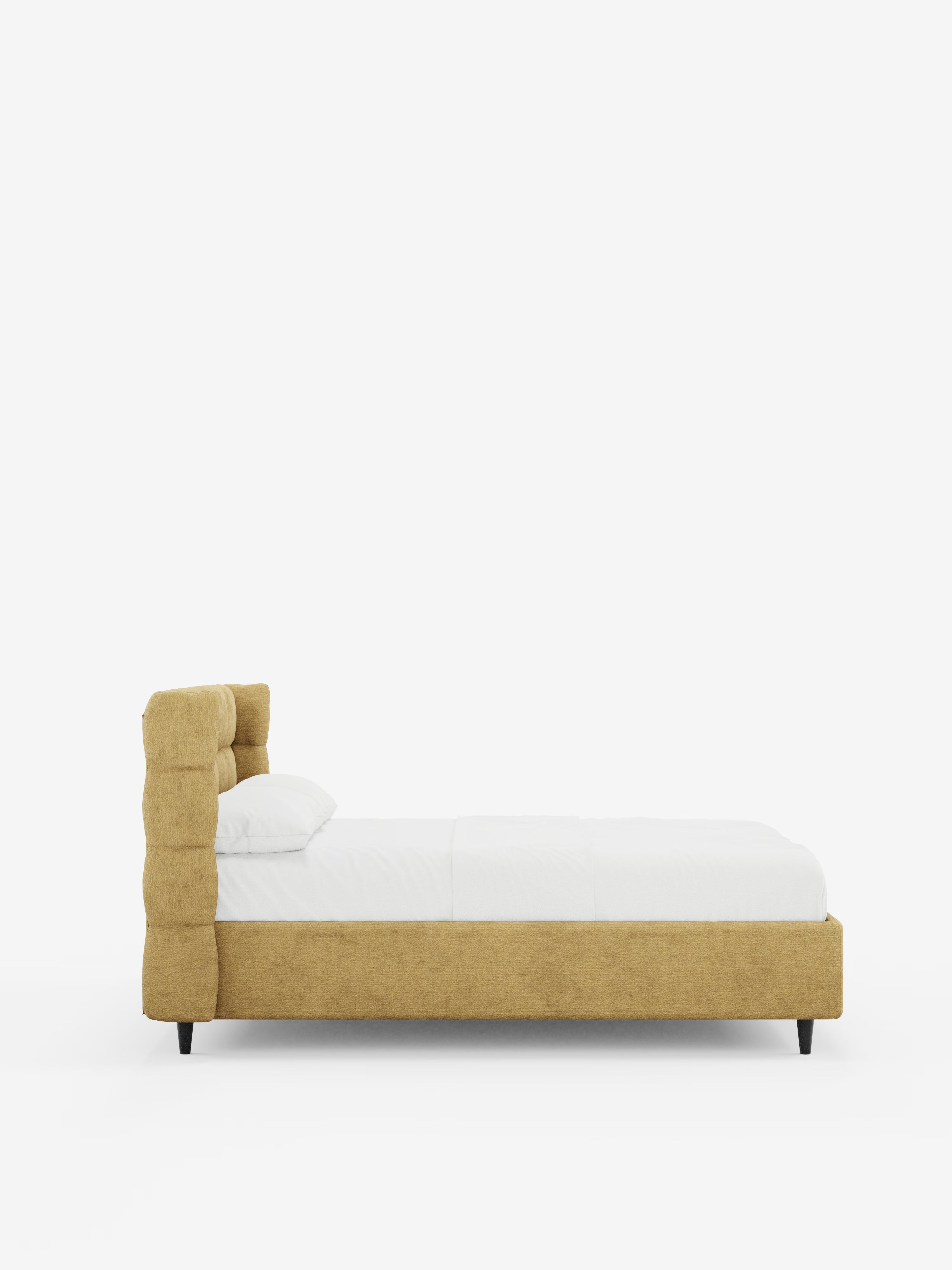 Vista laterale del letto imbottito RAGNAR con contenitore e testiera capitonné avvolgente di Letti.store, caratterizzato da un'elegante struttura imbottita in tessuto giallo senape certificato Oeko-Tex®. Il letto presenta una testiera capitonné avvolgente e poggia su gambe corte di colore nero. È abbinato a biancheria da letto bianca e un unico cuscino su uno sfondo bianco a tinta unita.