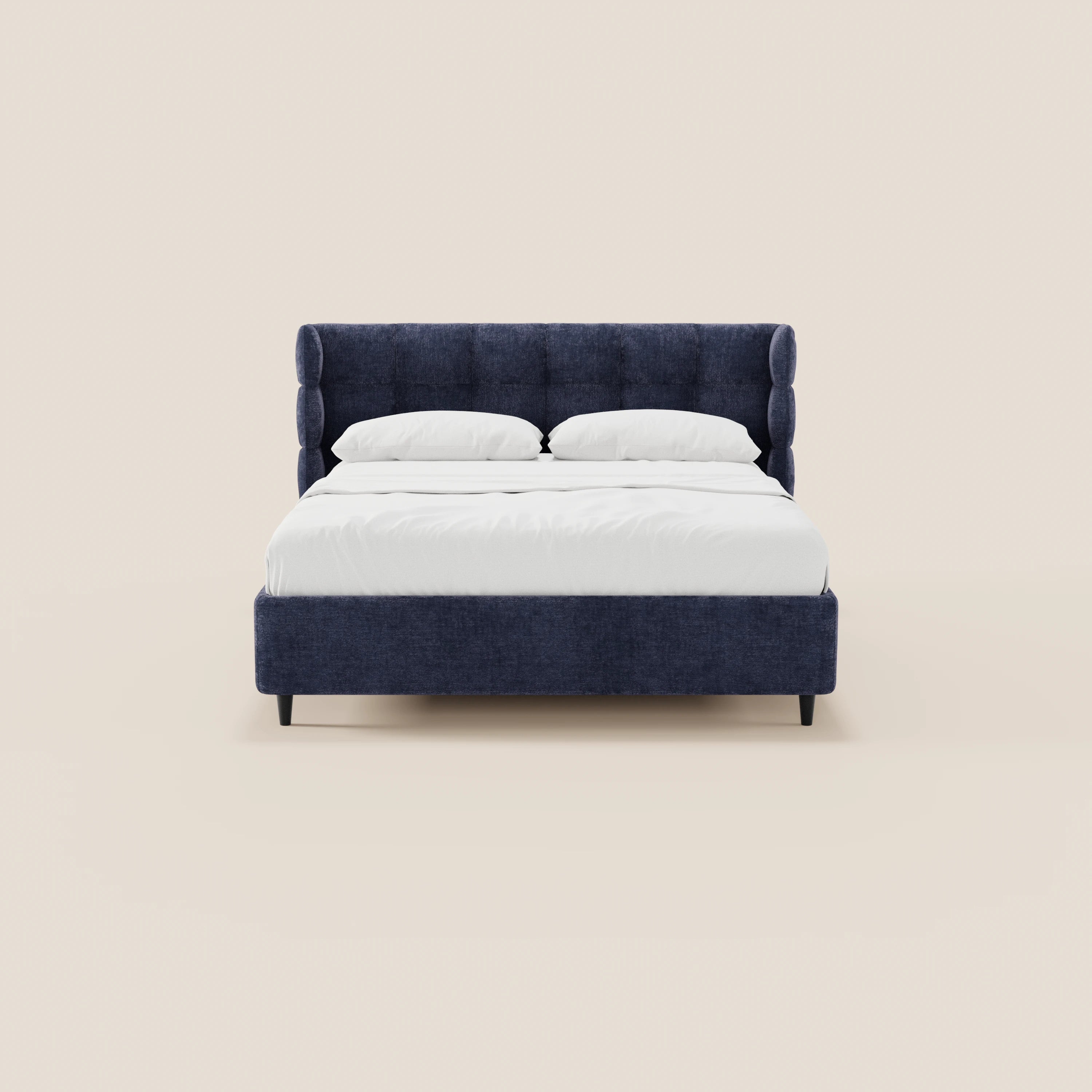 Il letto imbottito RAGNAR con contenitore e testiera capitonné avvolgente di Letti.store è presentato in blu navy con biancheria da letto bianca, due cuscini, gambe nere e un look minimalista e moderno su uno sfondo beige a tinta unita.