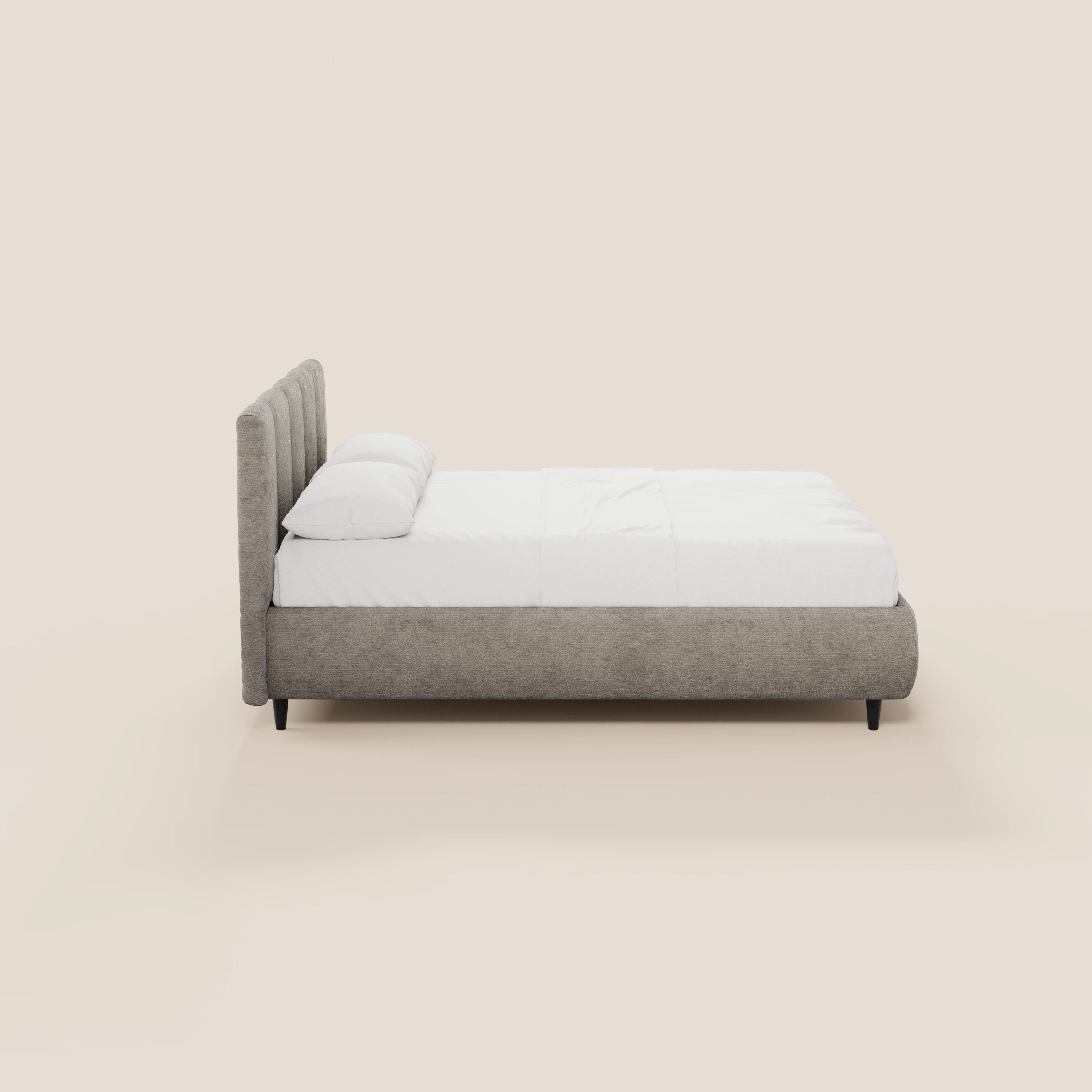Il letto imbottito ARKAM di Letti.store, con contenitore e testiera a lavorazione verticale in tessuto Oeko-Tex®, è presentato in grigio chiaro con materasso e cuscini bianchi, gambe corte nere e un design shabby chic su uno sfondo beige chiaro.