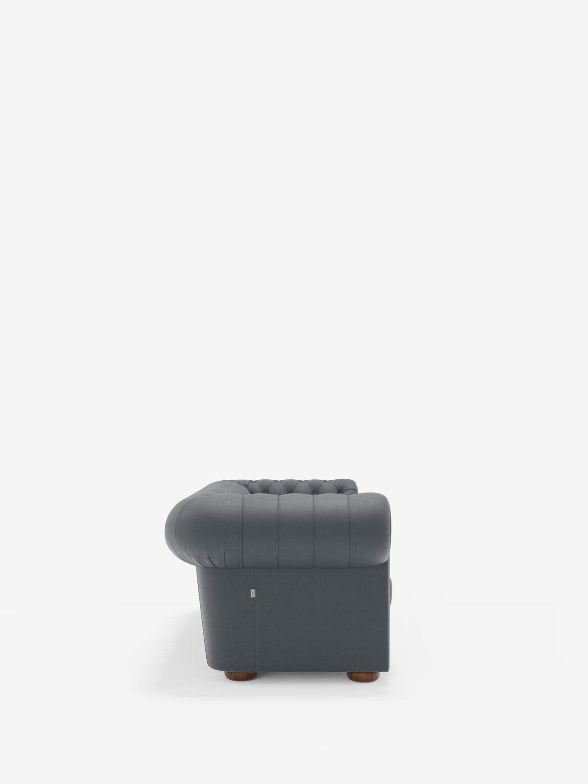 Una poltrona grigia scura con rivestimento a capitonné della collezione Chester – Divano Chesterfield in vera pelle spessorata a 2 e 3 posti di Divani.Store è raffigurata in una vista laterale su uno sfondo bianco a tinta unita. La poltrona presenta braccioli e schienale arrotondati, gambe in legno e un aspetto morbido e imbottito che esalta l’eleganza senza tempo della lavorazione artigianale in vera pelle spessorata.