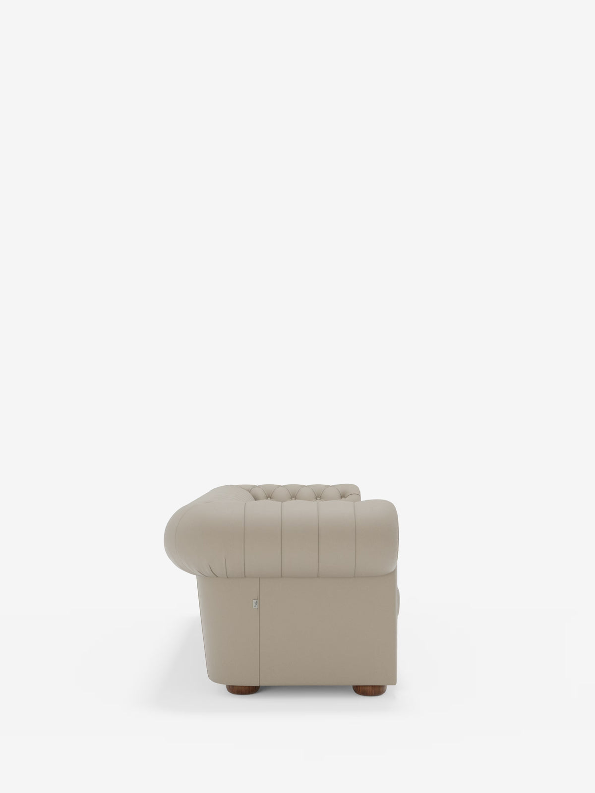 Vista laterale della “Chester 4 Posti 3 sedute in Vera Pelle – Chesterfield Capitonné Artigianale” di Divani.Store, una poltrona beige capitonné con braccioli arrotondati e piedini in legno, su uno sfondo bianco a tinta unita. La poltrona presenta cuciture a vista sui braccioli e sullo schienale, vanta una finitura liscia in vera pelle e incarna la classica maestria artigianale made in Italy.