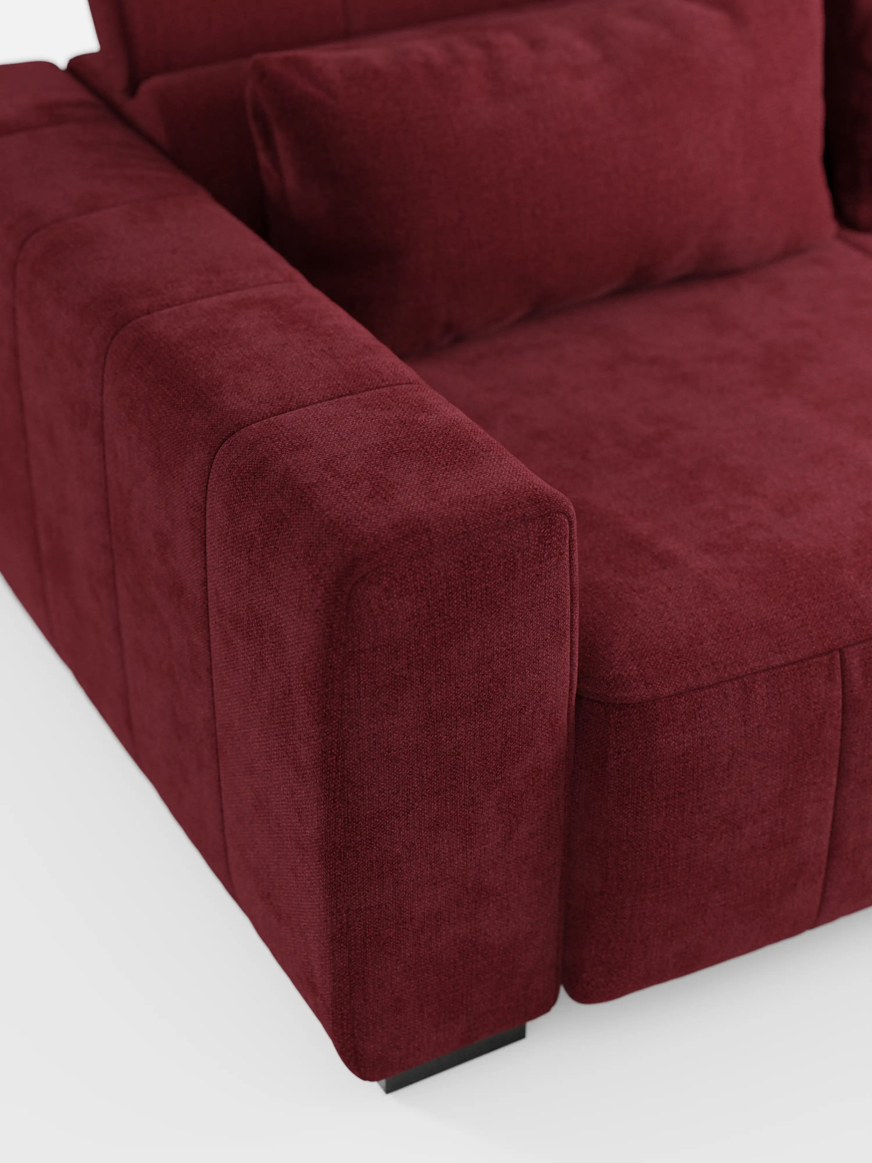 Primo piano del divano a 3 posti Doric di Divani.Store, che ne mette in risalto il design moderno rivestito in tessuto T23 rosso intenso e resistente alle macchie. L'immagine evidenzia il bracciolo, la seduta e una parte del cuscino dello schienale, rivelando un rivestimento soffice e morbido con cuciture a vista e bordi squadrati ben definiti. Le sedute allungabili tramite relax elettrico e i poggiatesta reclinabili sono parzialmente visibili su uno sfondo bianco.