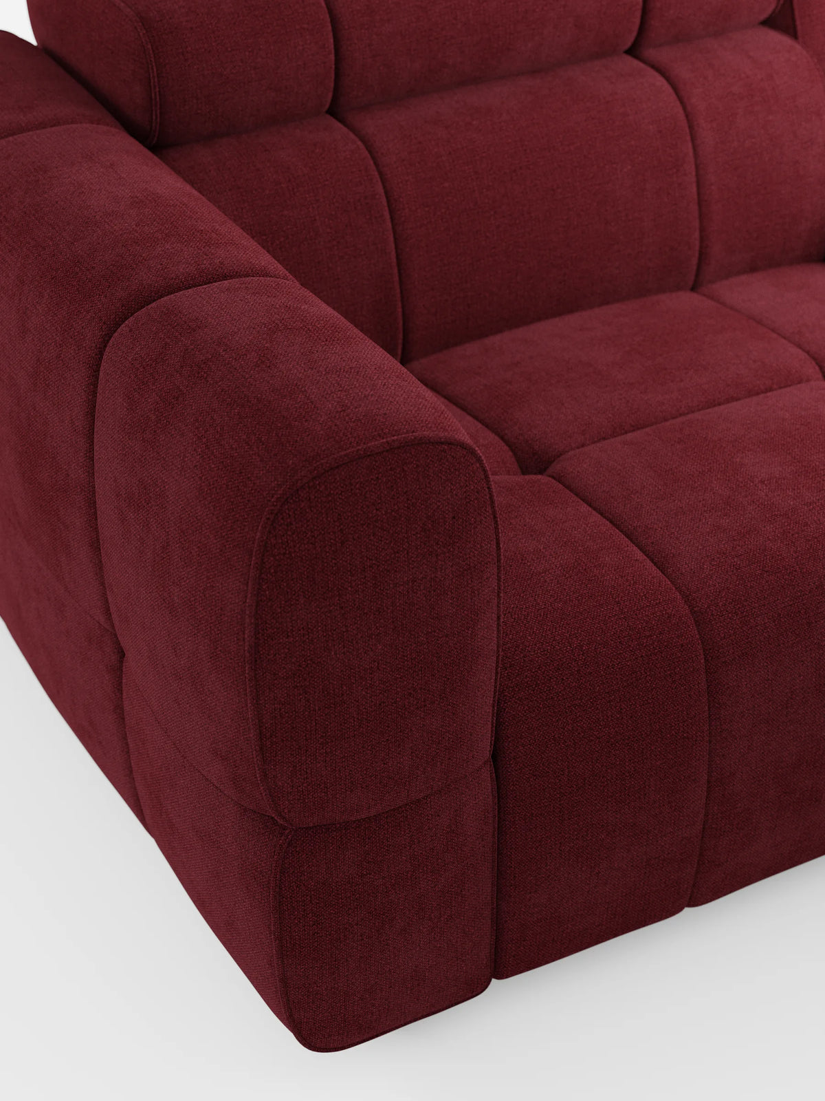 Un primo piano del divano modulare Giotto a 3 posti, di colore rosso intenso e dalla trama rigata, con poggiatesta reclinabili e funzione relax elettrica opzionale, rivestito in tessuto smacchiabile T23, caratterizzato da cuscini spessi con trapuntatura a quadrati e braccioli arrotondati su uno sfondo chiaro.