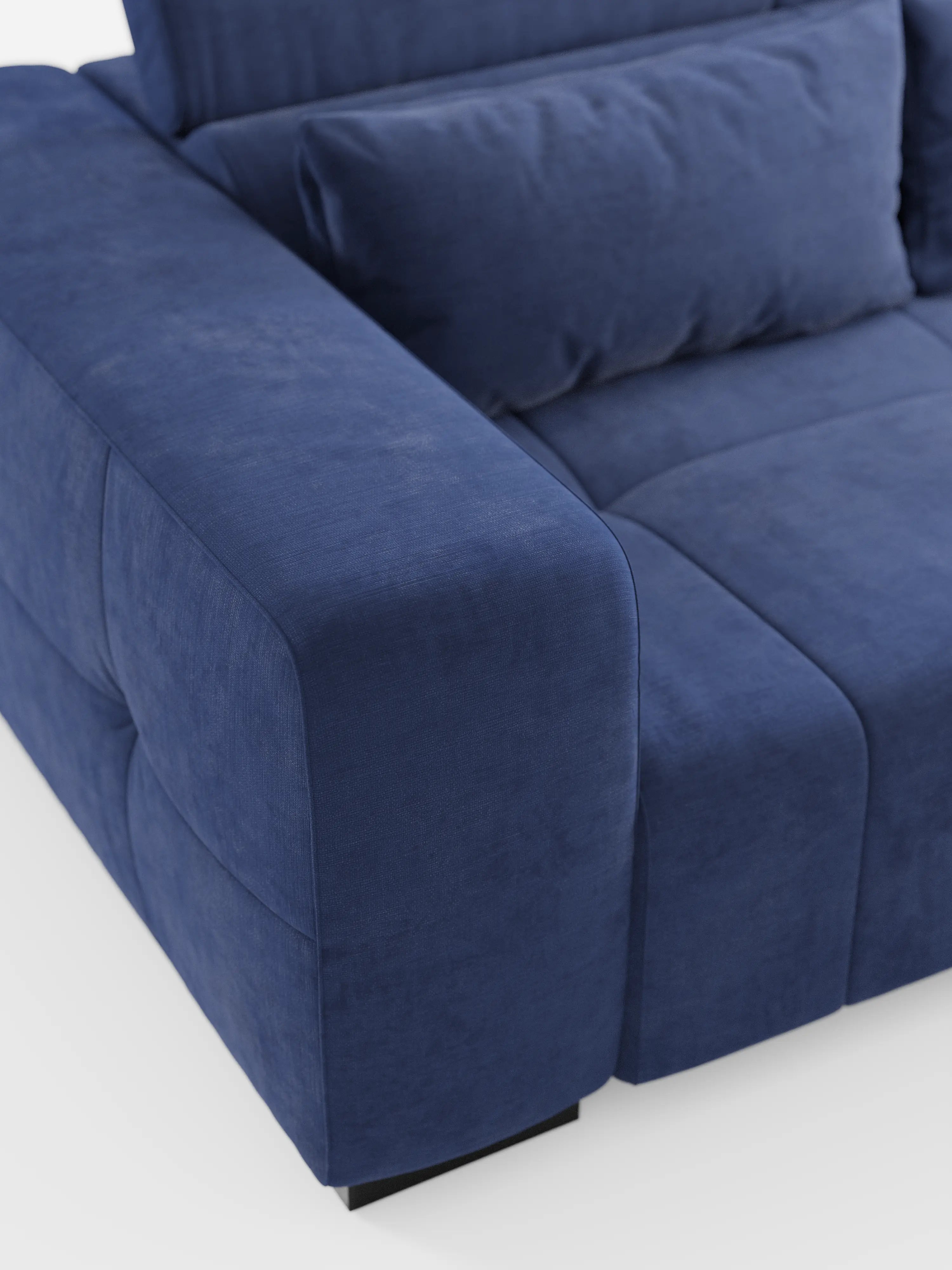 Primo piano del divano Monarch con funzione relax elettrica per l’allungamento delle sedute e poggiatesta reclinabile, realizzato in morbido tessuto smacchiabile T31 di Divani.Store, che mette in risalto il bracciolo sinistro, il cuscino di seduta, lo schienale e un cuscino rettangolare abbinato. Il tessuto blu, morbido e liscio, è cucito con cura e si abbina perfettamente al design contemporaneo squadrato del divano, che risalta sullo sfondo bianco.