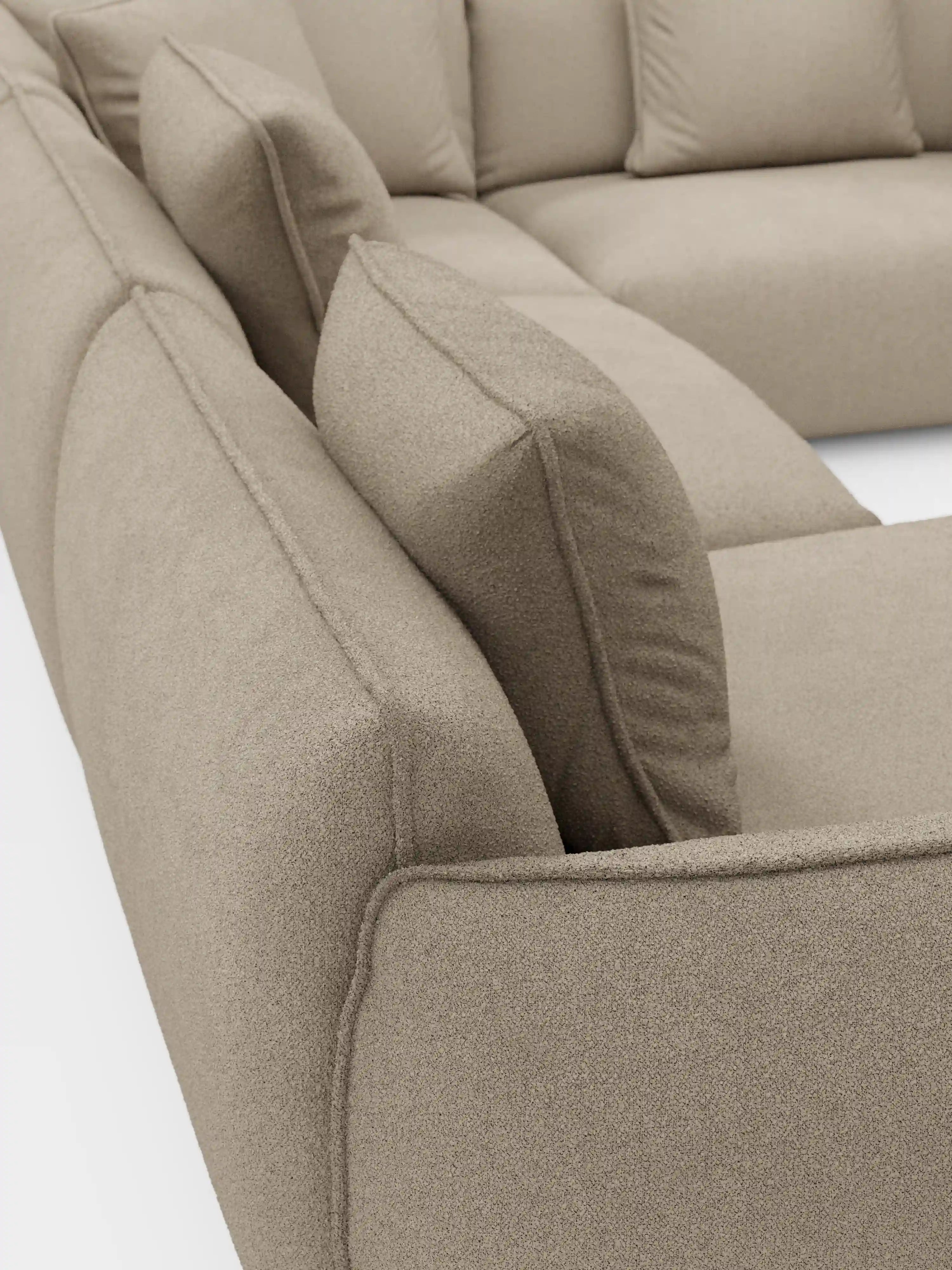 Primo piano del divano angolare panoramico componibile Nimbus con penisola e angolo in tessuto smacchiabile t33 di Divani.Store, caratterizzato da un design modulare beige con morbidi cuscini quadrati e rivestimento in tessuto testurizzato. Su uno sfondo bianco, l’immagine mette in risalto le linee eleganti e le sezioni di seduta e schienale realizzate con cura, a testimonianza della raffinata maestria artigianale del Made in Italy.