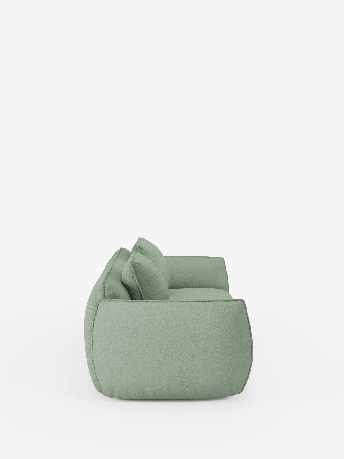 Vista laterale di un moderno divano Nimbus a 3 posti, modulare e componibile, da 250 cm, di colore verde chiaro, di Divani.Store, rivestito in tessuto T33 effetto cotone, sfoderabile e antimacchia, con due cuscini dello schienale, su uno sfondo bianco a tinta unita. Il divano presenta una forma bassa e squadrata e bordi morbidi e arrotondati che gli conferiscono un aspetto accogliente e contemporaneo.