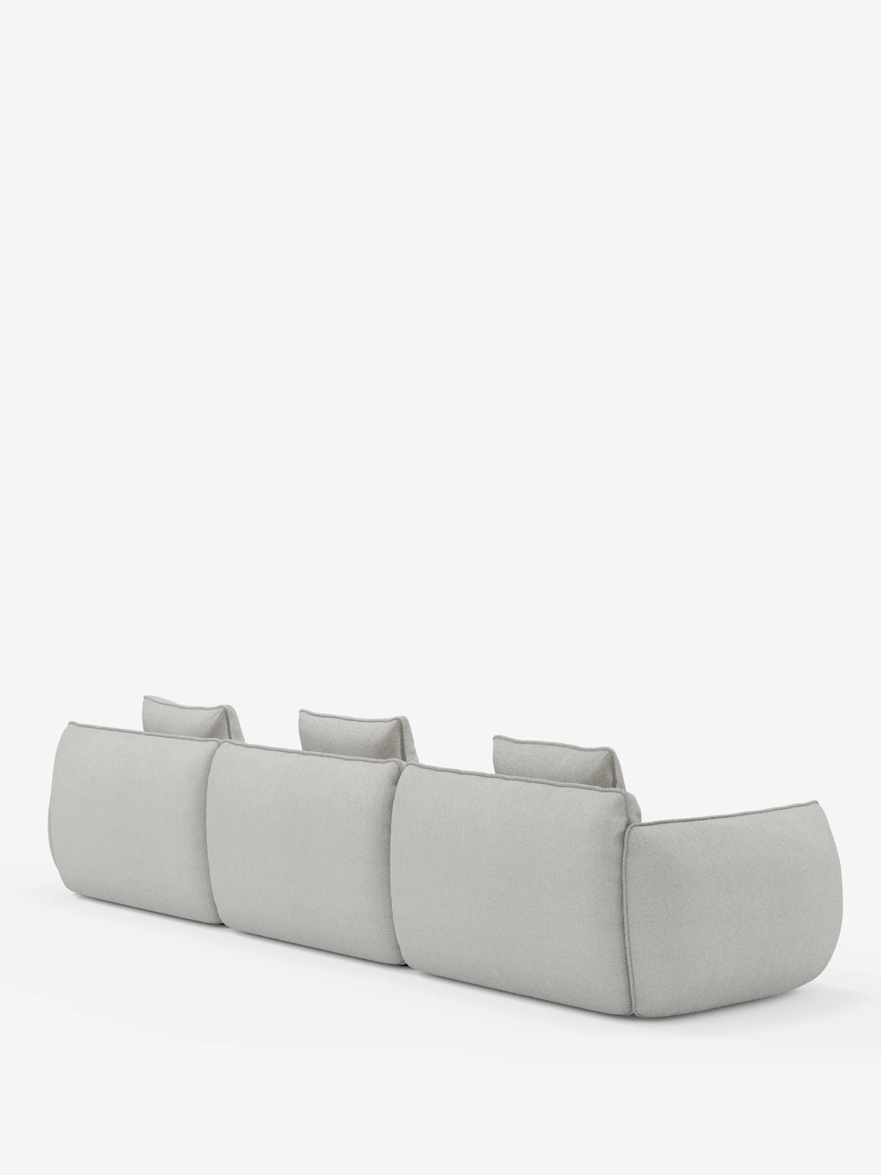 Un divano angolare contemporaneo di colore grigio chiaro, il modello Nimbus di Divani.Store, caratterizzato da un design minimalista e dal profilo ribassato, con schienali e braccioli imbottiti rivestiti in morbido tessuto effetto cotone resistente alle macchie. Immagine della parte posteriore su sfondo bianco.