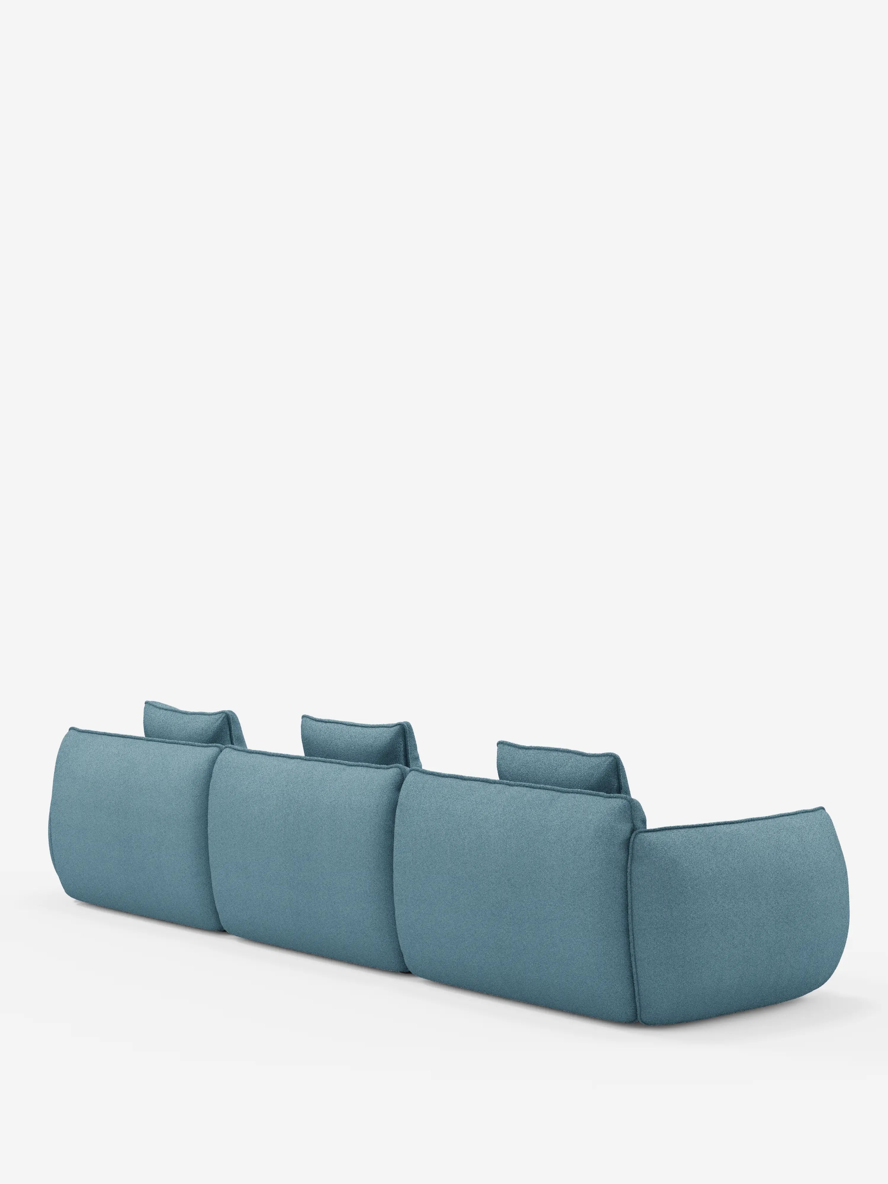 Il *divano angolare con penisola componibile Nimbus*, un modello contemporaneo e minimalista in tessuto blu di Divani.Store, è ripreso in una vista posteriore su uno sfondo bianco a tinta unita. Il divano presenta un profilo basso, bordi arrotondati e tre cuscini dello schienale, mettendo in risalto il suo design pulito, senza gambe visibili né dettagli sui braccioli. Realizzato in morbido rivestimento T33 effetto cotone, resistente alle macchie.