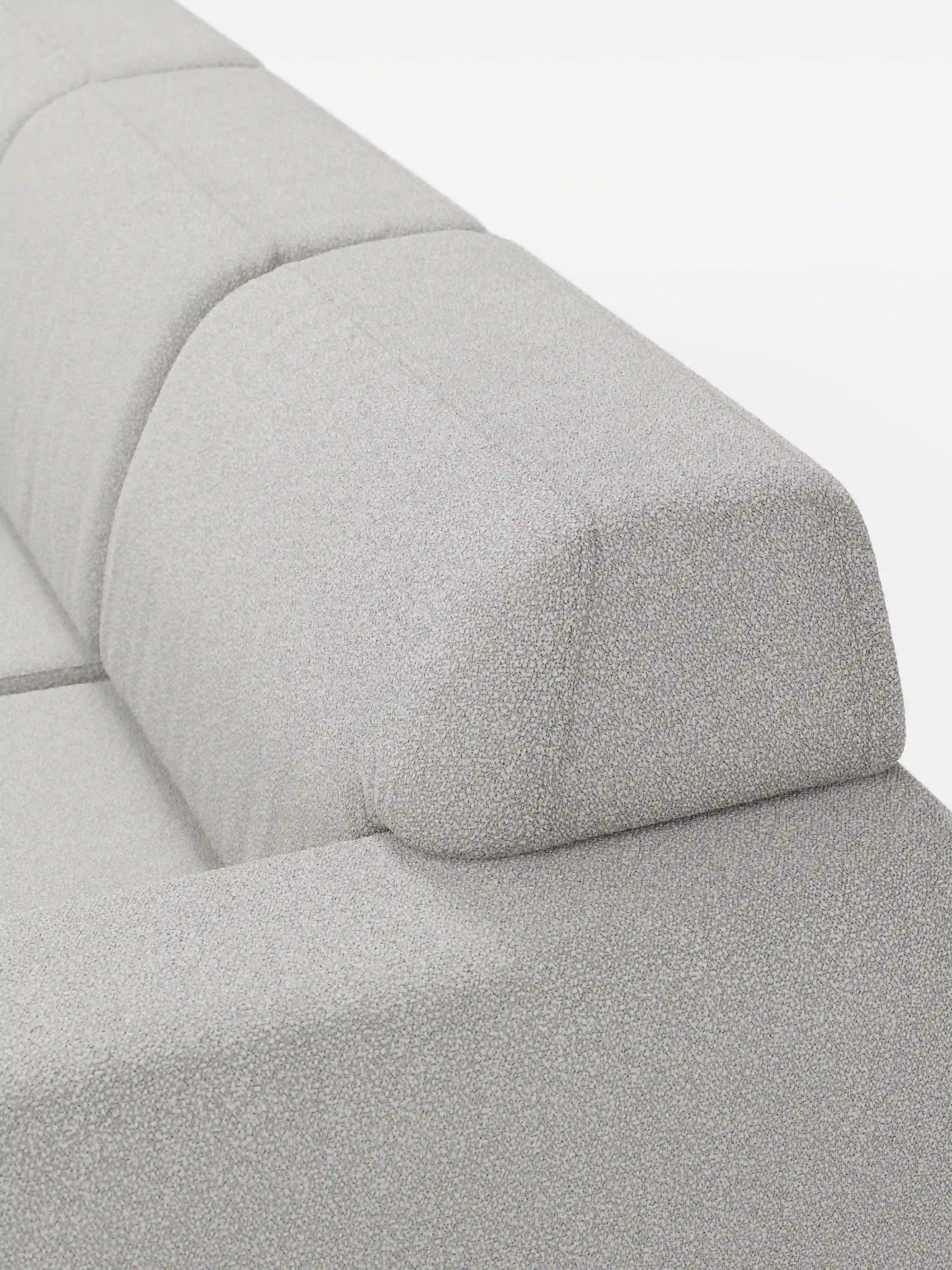 Primo piano del divano angolare Orbit con penisola reversibile e tutte le sedute allungabili in tessuto smacchiabile effetto cotone T33 di Divani.Store, caratterizzato da un moderno schienale imbottito grigio chiaro dalle linee pulite e da un cuscino poggiatesta rettangolare angolare. Il tessuto antimacchia effetto cotone presenta una texture delicatamente ruvida, mentre il design minimalista risalta sullo sfondo bianco a tinta unita.