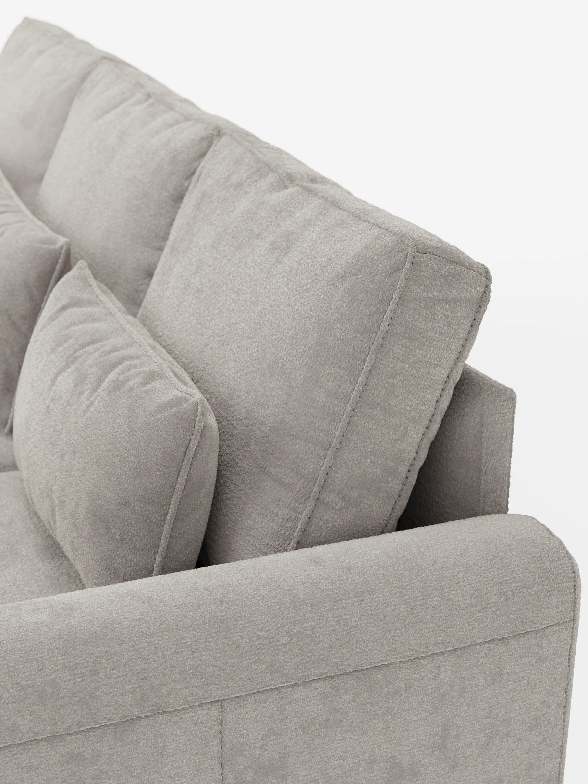 Primo piano di un divano letto Ottaviano in tessuto grigio testurizzato con letto estraibile - penisola reversibile e contenitore in tessuto materico lavabile, che mostra i cuscini dello schienale, un cuscino decorativo e il bracciolo laterale su uno sfondo bianco.