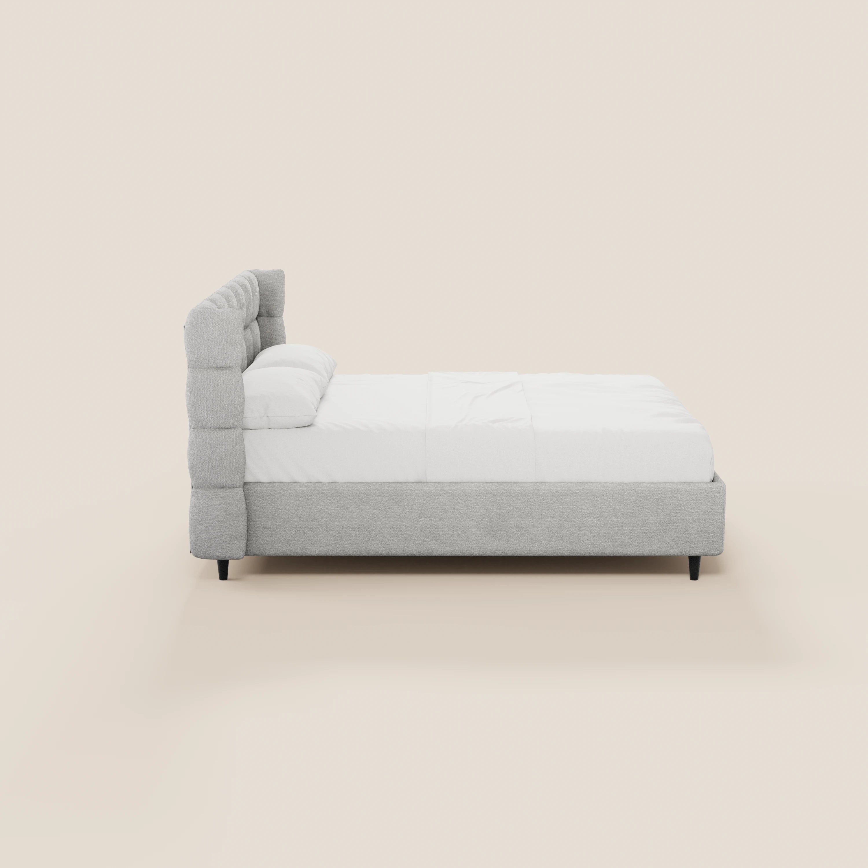 Il letto imbottito RAGNAR di Letti.store, con vano contenitore e testiera capitonné avvolgente in elegante tessuto Oeko-Tex®, è raffigurato di profilo con rivestimento grigio chiaro, gambe nere, biancheria da letto bianca e sfondo beige.