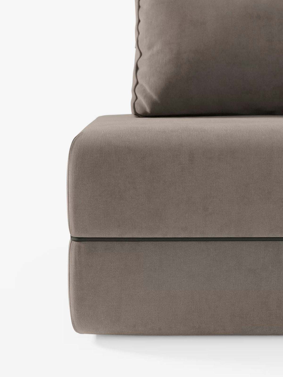 Un primo piano della poltrona letto Rift con materasso alto 24 cm e memory foam di Divani.Store mette in risalto l’angolo destro di un cuscino di seduta imbottito color taupe e un cuscino coordinato con bordi a passamaneria, su uno sfondo bianco a tinta unita. Il tessuto T31, liscio, morbido e smacchiabile, è valorizzato da sottili giochi di ombra: un’elegante soluzione trasformabile con schienale mobile che coniuga perfettamente comfort e stile per gli spazi abitativi contemporanei.