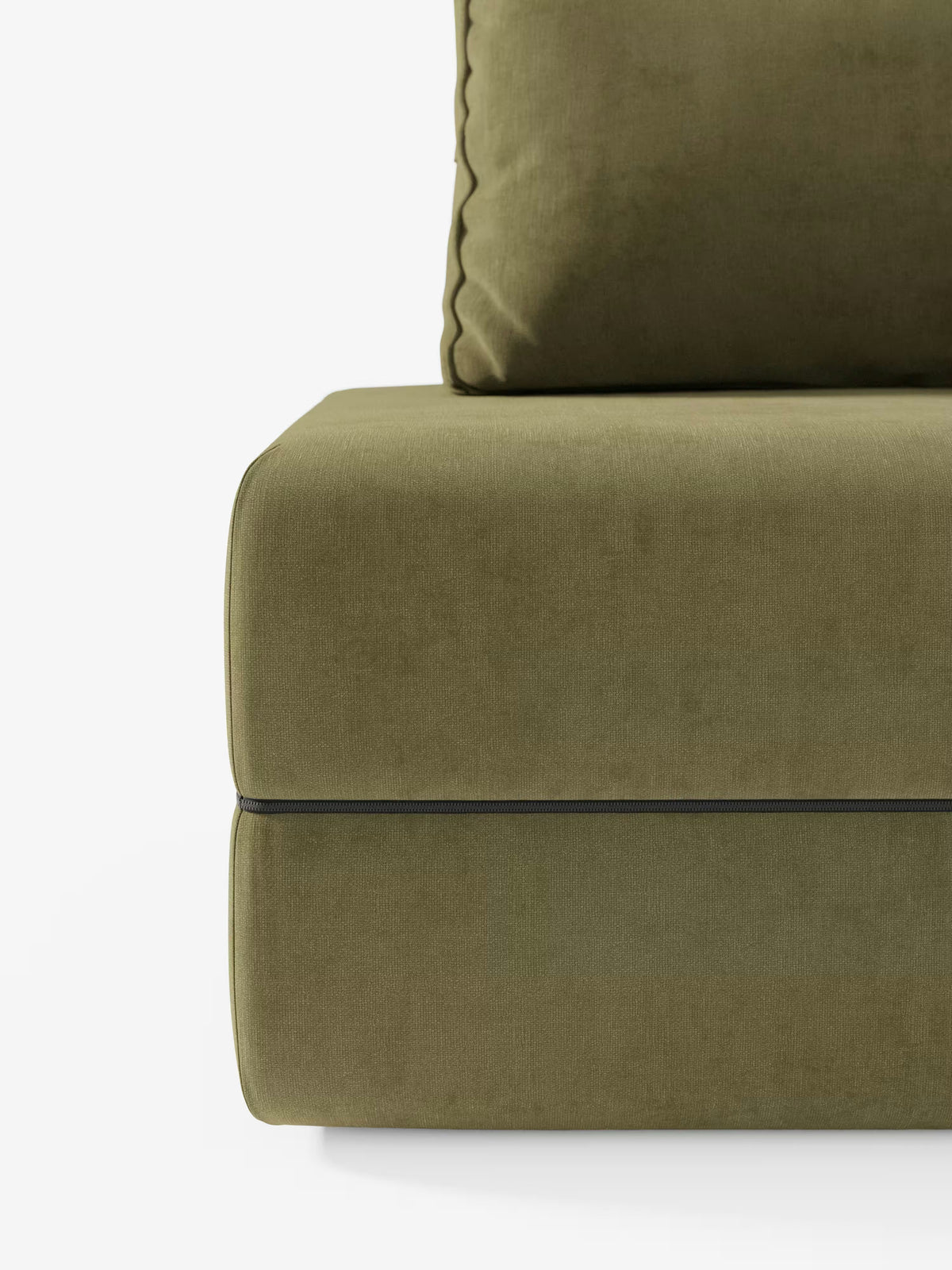 Un primo piano della poltrona letto Rift di Divani.Store ne mette in risalto il design squadrato e moderno, realizzato in tessuto T31 verde oliva resistente alle macchie, valorizzato dalla cucitura a vista del cuscino di seduta e dal cuscino dello schienale in tinta. Il morbido rivestimento, simile al velluto, si abbina perfettamente alle linee pulite e allo schienale reclinabile, mentre il materasso in memory foam alto 24 cm aggiunge versatilità e stile. Il tutto su uno sfondo bianco a tinta unita.