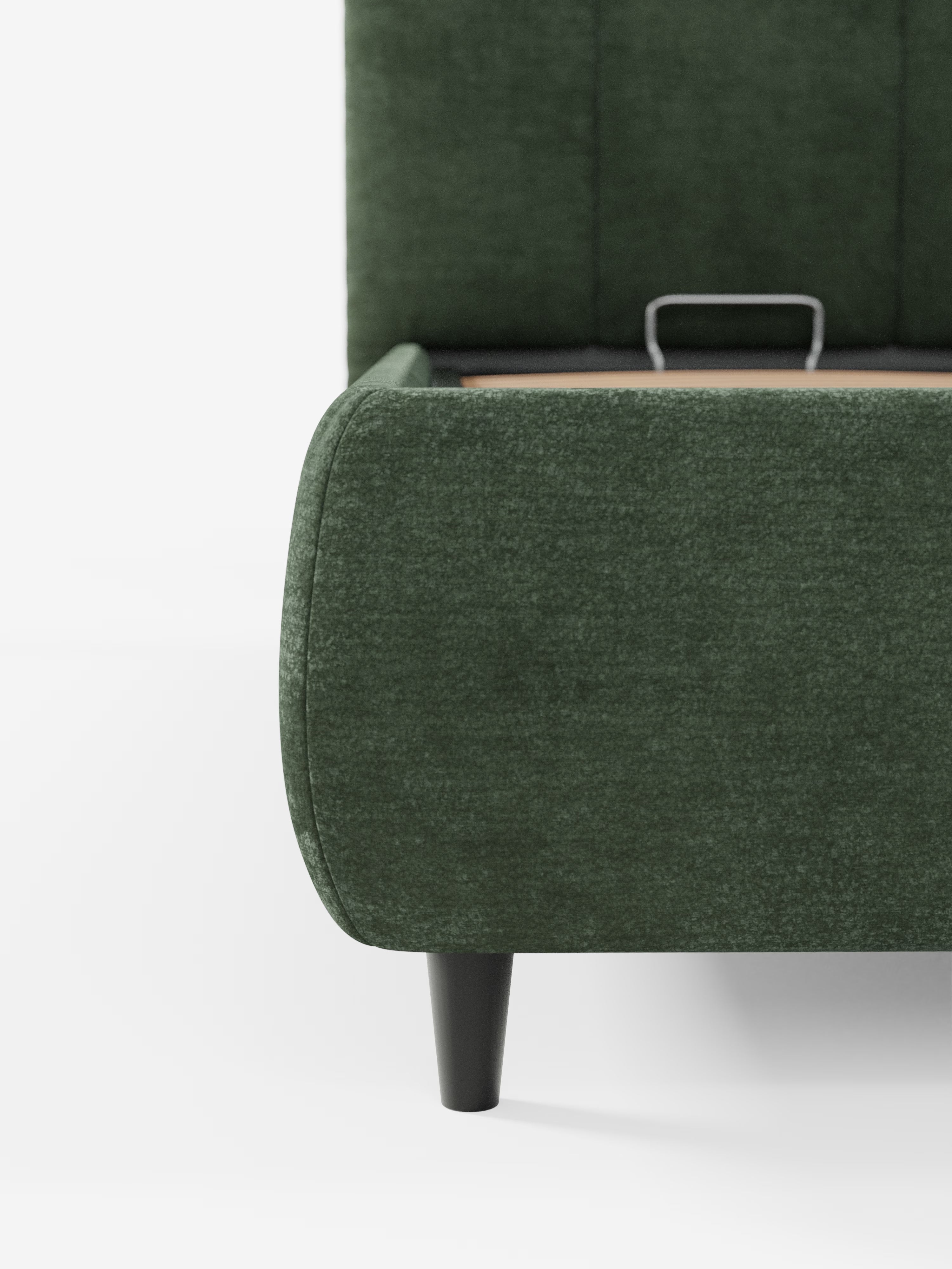 Primo piano dell'angolo del letto imbottito ARKAM con vano contenitore e testiera a cuciture verticali di Letti.store, caratterizzato da un rivestimento verde certificato Oeko-Tex® e da gambe in legno nero. È visibile un cassetto aperto dotato di una piccola maniglia in metallo, mentre lo sfondo bianco a tinta unita mette in risalto l’elegante testiera imbottita con cuciture verticali e il raffinato design shabby chic.