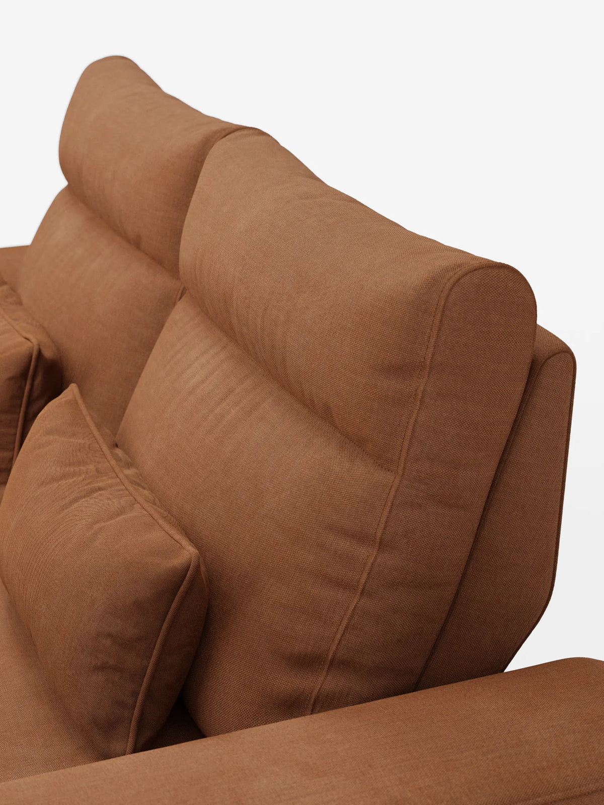 Un primo piano del divano Ischia a 3 posti con pouf estraibile e schienali traslanti, rivestito in tessuto misto lino smacchiabile color terracotta con effetto testurizzato, caratterizzato da schienali regolabili e da un cuscino cilindrico abbinato su uno sfondo a tinta unita.