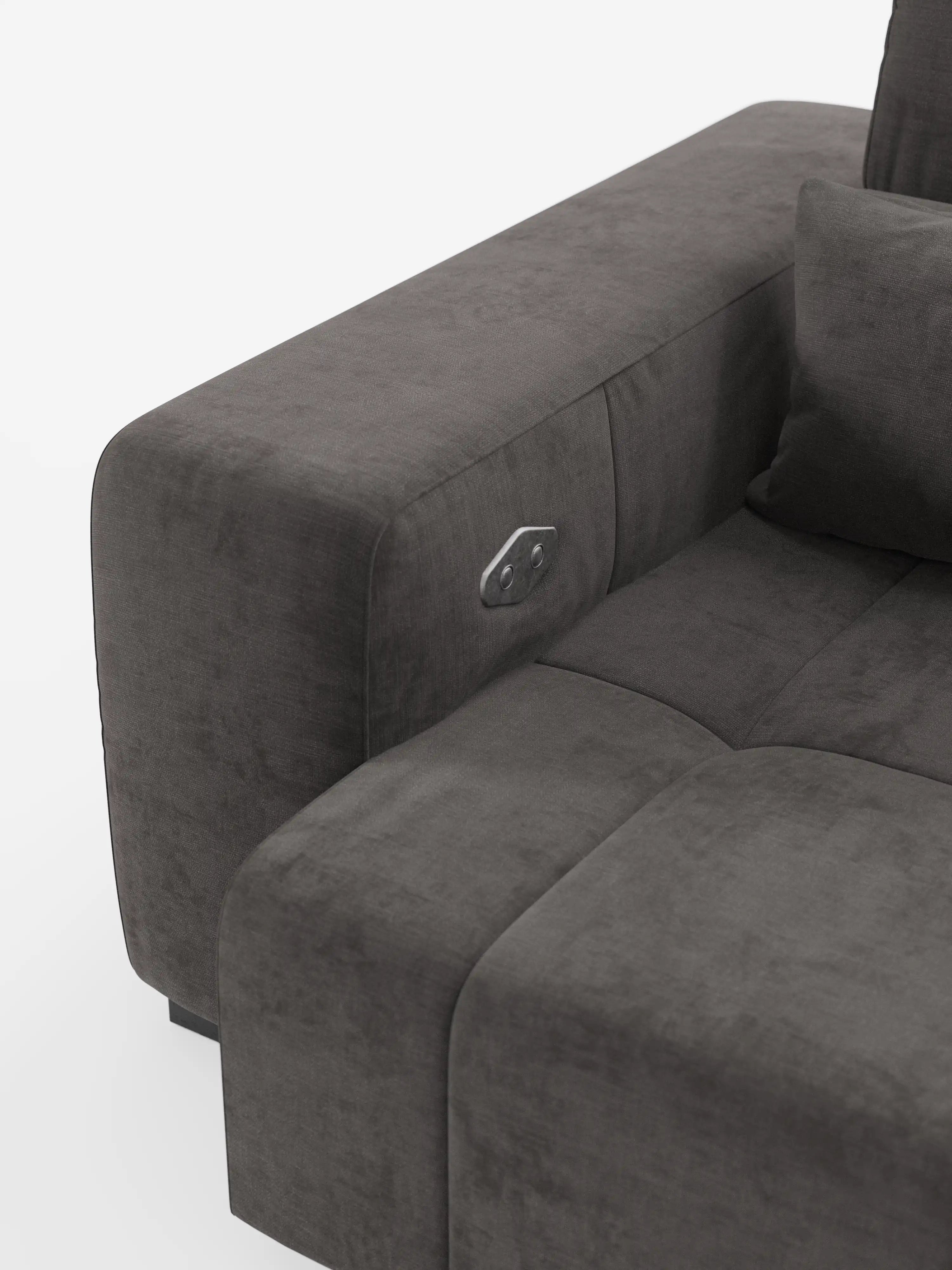 Primo piano del bracciolo del divano Monarch con funzione relax elettrica per l’allungamento delle sedute e poggiatesta reclinabile, realizzato in morbido tessuto lavabile T31 di Divani.Store, qui raffigurato in una moderna finitura in tessuto grigio scuro con cuscino coordinato. Il bracciolo è dotato di un pannello di comando metallico integrato, ideale per regolare le funzioni di reclinazione elettrica del divano. Lo sfondo è bianco e minimalista.