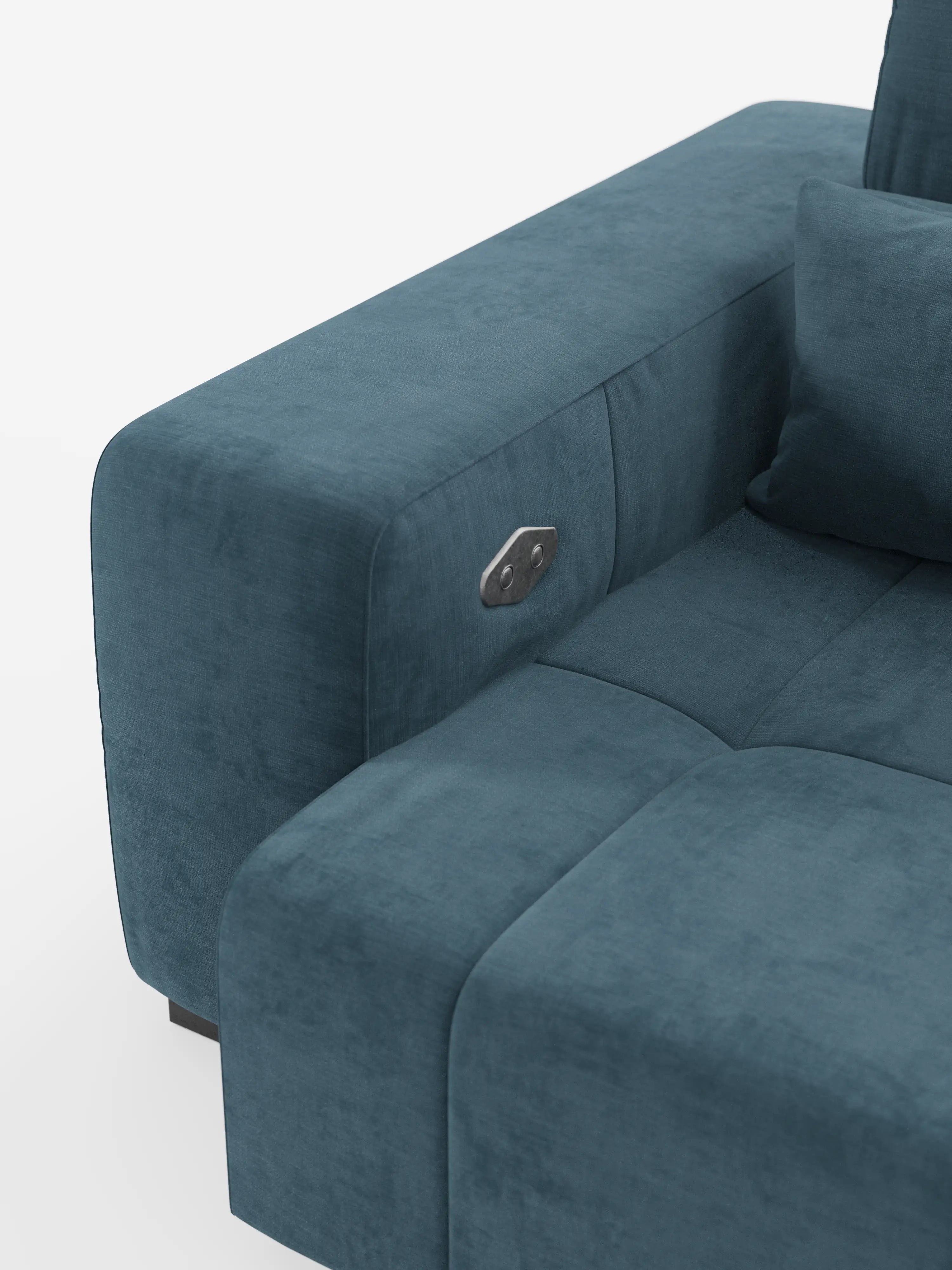 Primo piano del bracciolo e del cuscino di seduta del divano Monarch con relax elettrico per l’allungamento delle sedute e poggiatesta reclinabile in morbido tessuto smacchiabile T31 di Divani.Store, qui raffigurato in velluto color verde acqua. Sul bracciolo è montato un pannello di comando rettangolare con pulsanti, che mette in risalto le innovative caratteristiche di comfort di questo divano contemporaneo. Un cuscino coordinato spunta dall’angolo su uno sfondo bianco a tinta unita.