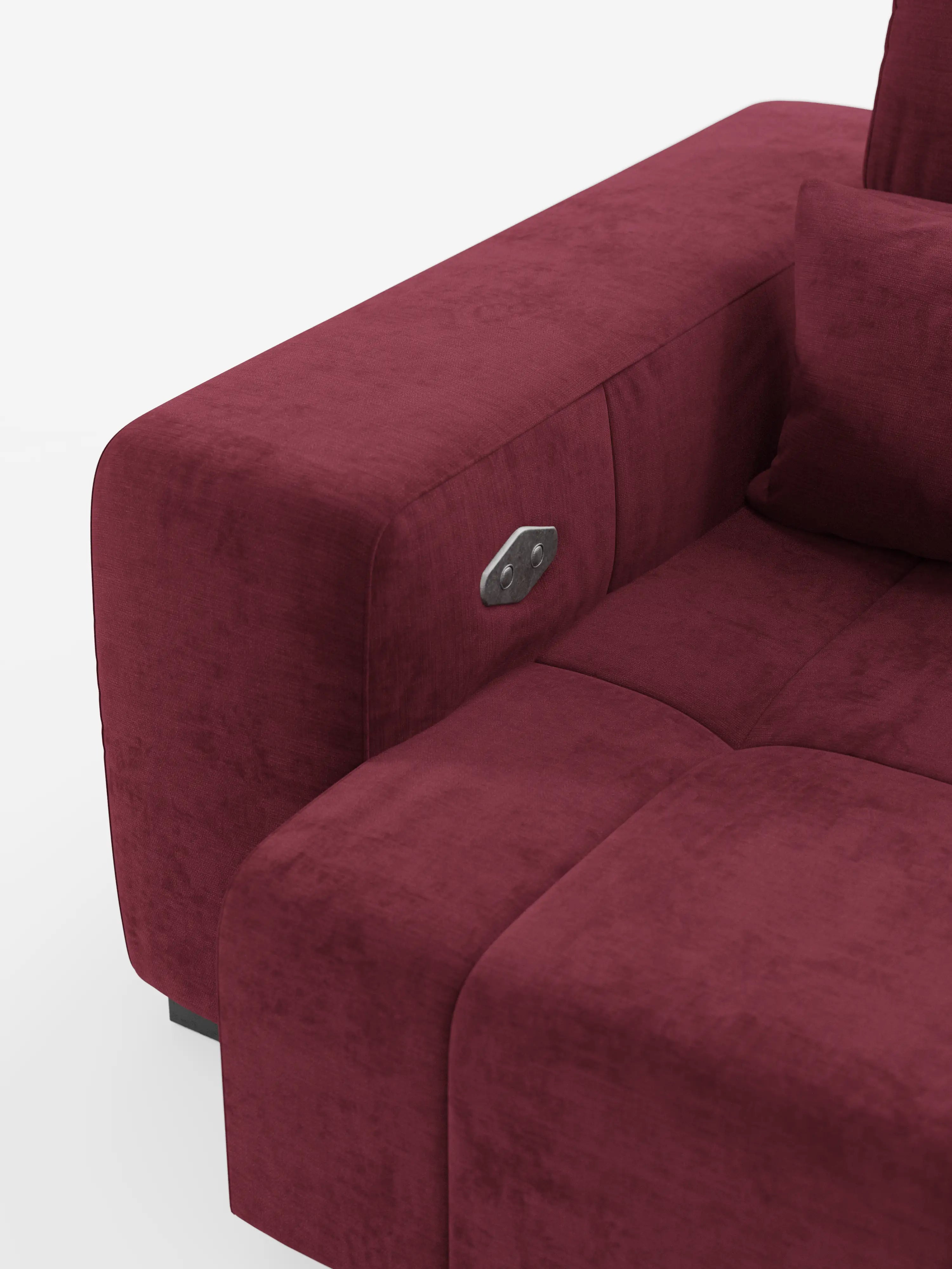 Un primo piano del bracciolo del divano Divani.Divano Monarch con funzione relax elettrica per l'allungamento delle sedute e poggiatesta reclinabile, caratterizzato da rivestimento in morbido tessuto T31 color bordeaux resistente alle macchie, cuciture a vista, cuscino soffice, pannello di controllo in metallo integrato e finitura testurizzata su sfondo bianco a tinta unita.