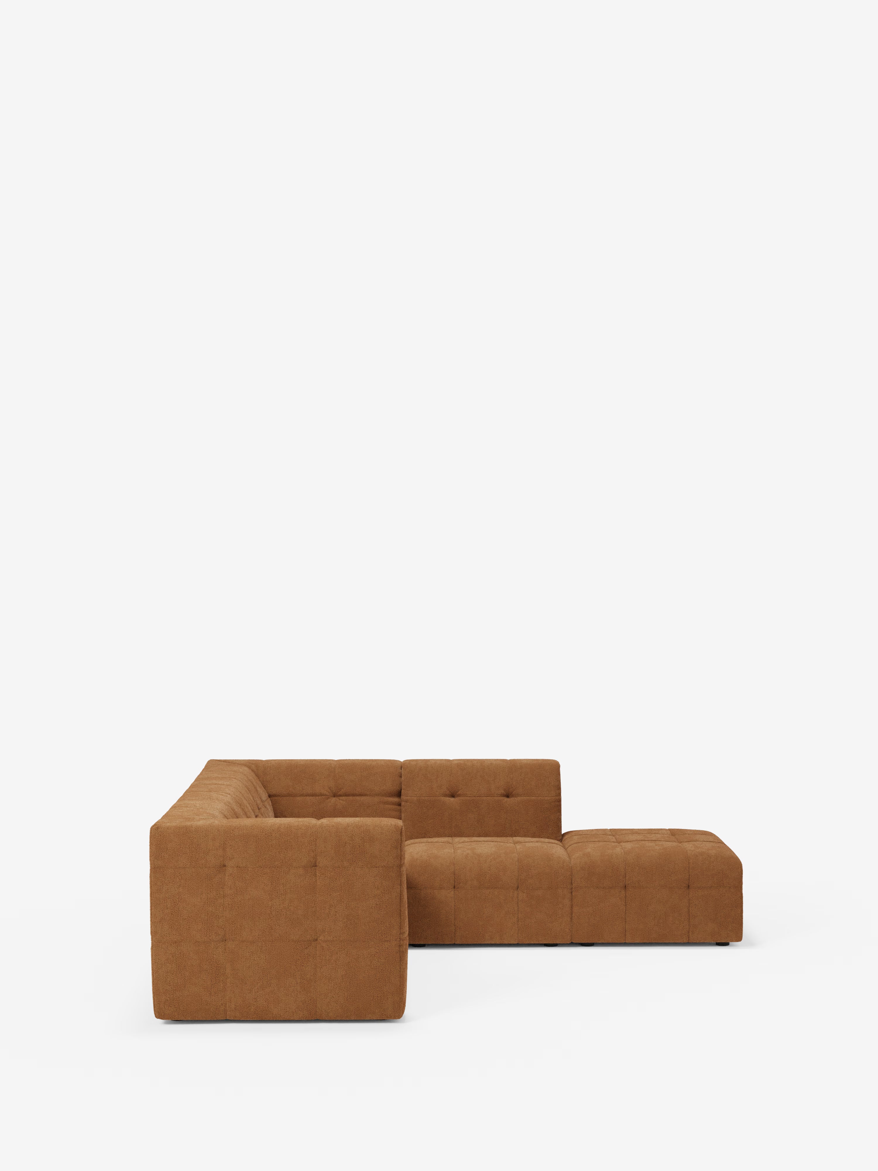 Un moderno divano angolare componibile e modulare “Mosaic” di colore marrone, firmato Divani.Il modello Store, caratterizzato da un design minimalista a forma di L con cuscini quadrati capitonné (imbottiti) e schienali bassi, rivestito in un morbido tessuto bouclé antimacchia (T21), è presentato su uno sfondo bianco a tinta unita.