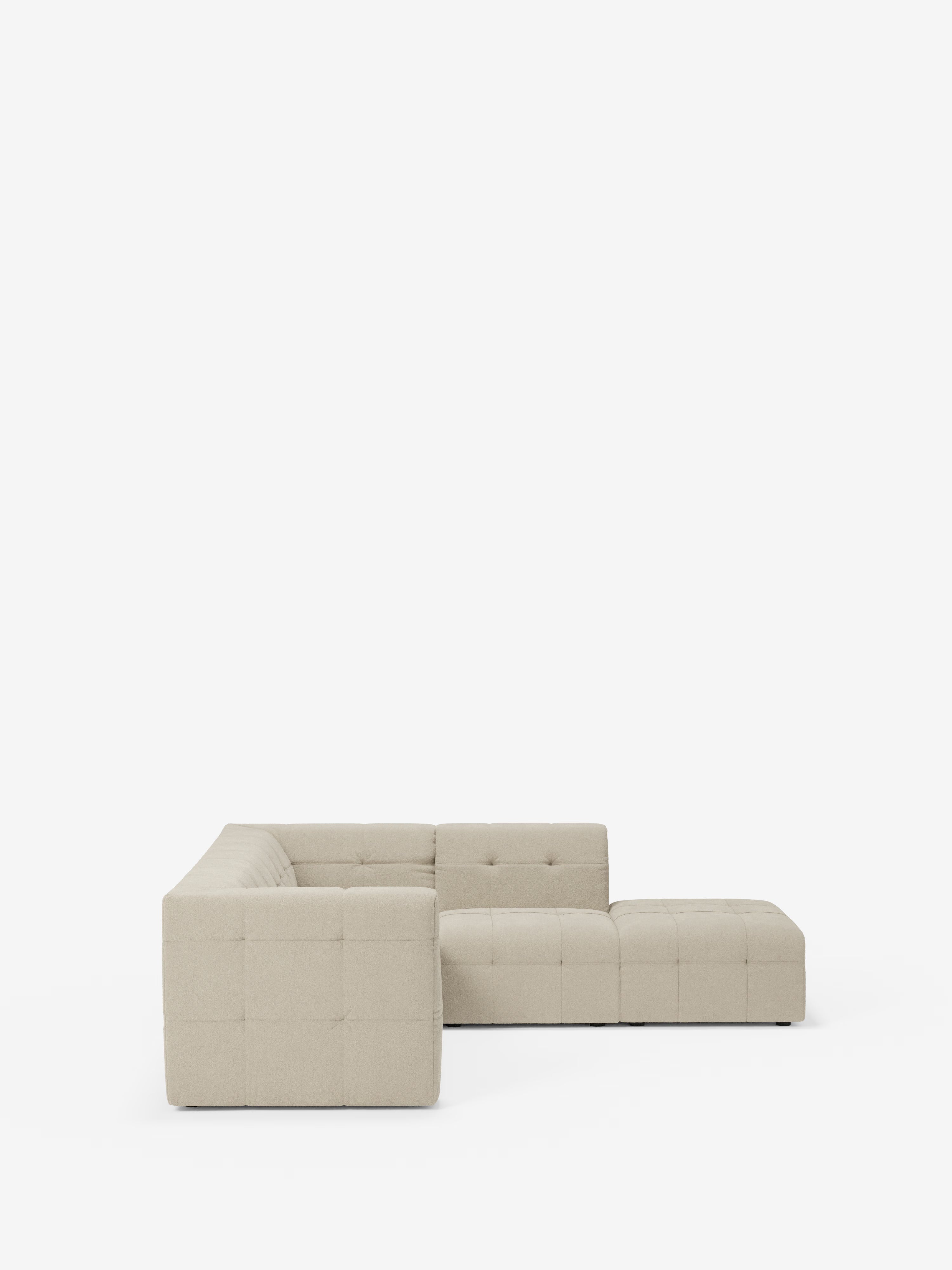 Un moderno divano angolare componibile e modulare Mosaic, color beige, in bouclé: capitonné e design in tessuto antimacchia T21 di Divani.Store, si staglia su uno sfondo bianco a tinta unita. Caratterizzato da linee pulite, braccioli bassi e squadrati e cinque segmenti modulari rivestiti in lussuoso tessuto bouclé con cuscini trapuntati, questo divano crea un’ampia zona salotto sulla sinistra e una chaise longue allungata sulla destra.