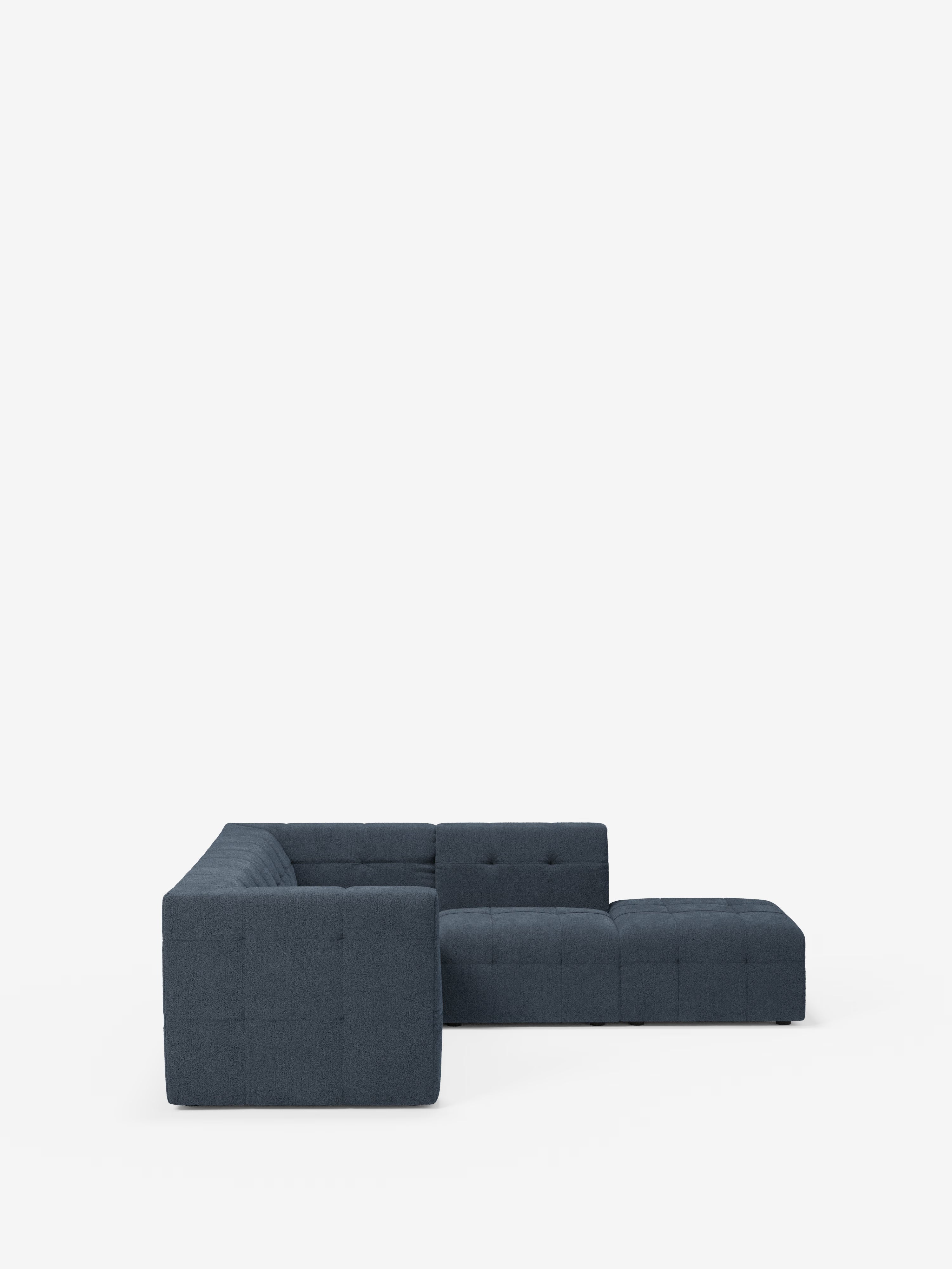 Un divano angolare componibile e modulare Mosaic in bouclé, dal colore blu scuro e dallo stile contemporaneo, realizzato da Divani.Store, è esposto su uno sfondo bianco. Questo divano componibile presenta un rivestimento capitonné, linee pulite, cuscini spessi e un design modulare con una chaise longue estesa sul lato destro, il tutto realizzato in tessuto T21 facile da pulire.
