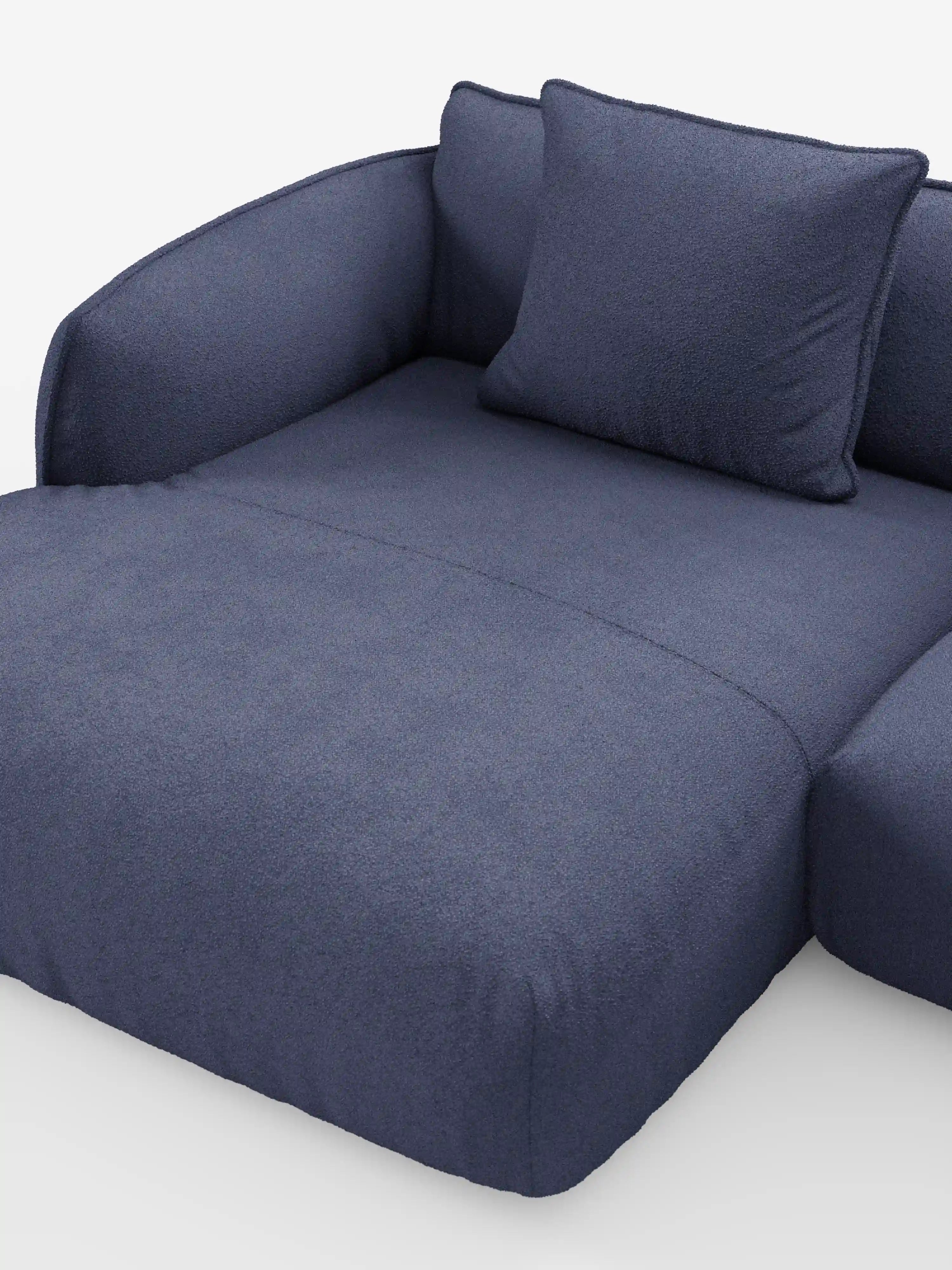 Un divano angolare panoramico componibile Nimbus, spazioso e dal design contemporaneo, in blu navy con penisola e angolo, rivestito in tessuto smacchiabile T33 di Divani.Store, caratterizzato da ampi cuscini, braccioli dalle linee morbidamente arrotondate e un cuscino coordinato, il tutto su uno sfondo bianco a tinta unita. Il rivestimento morbido e dalla trama ricca ne esalta il comfort accogliente, rendendolo la scelta ideale per chi è alla ricerca di un design italiano versatile.