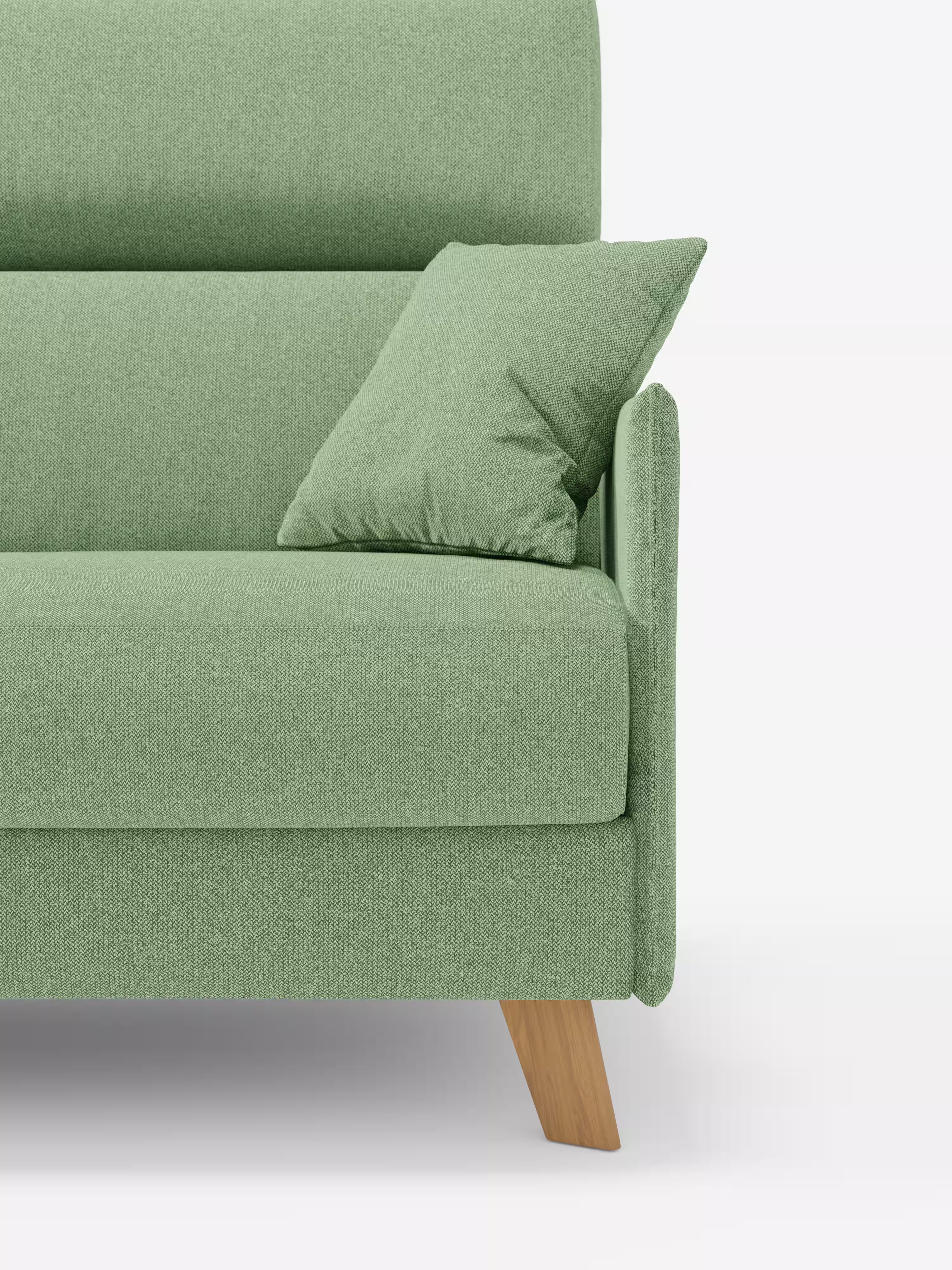 Un primo piano del divano letto matrimoniale Sole dal design compatto di Divani.Store, rivestito in tessuto verde smacchiabile T23 con un cuscino abbinato appoggiato al bracciolo. La seduta, lo schienale e uno dei braccioli, parzialmente visibili, mettono in risalto le gambe angolari in legno e le linee pulite del divano, su uno sfondo bianco a tinta unita.