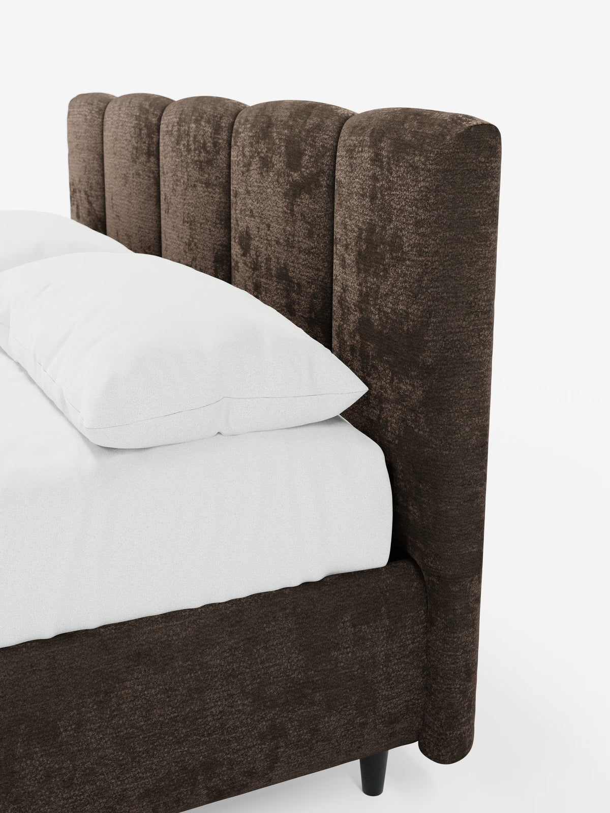 Il letto imbottito ARKAM con contenitore e testiera a lavorazione verticale di Letti.store presenta una testiera alta, con canalature verticali, rivestita in un morbido tessuto marrone testurizzato certificato Oeko-Tex®. Il letto è abbinato a biancheria da letto e cuscini di un bianco brillante e poggia su gambe corte e scure, di cui è visibile solo una parte su uno sfondo bianco a tinta unita. Il suo design incarna l’eleganza shabby chic e la praticità della funzionalità contenitiva.