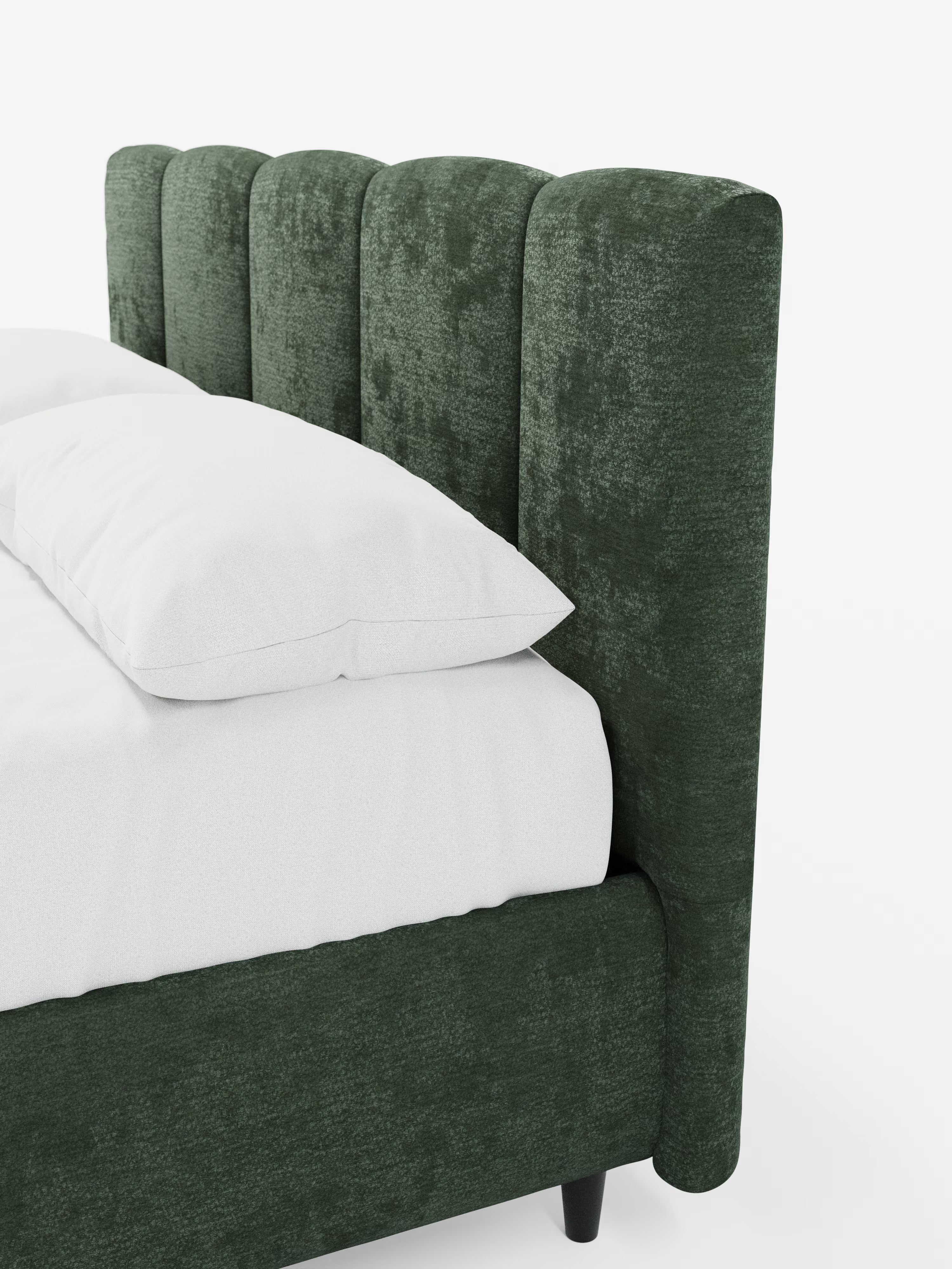 Un primo piano del letto imbottito ARKAM con contenitore e testiera a lavorazione verticale di Letti.store, caratterizzato da un’alta testiera imbottita verde scuro con trapuntatura a canali e da una struttura coordinata. Il letto è rivestito con biancheria da letto bianca e un cuscino in evidenza, su uno sfondo bianco. Questo design moderno e lussuoso esalta lo stile shabby chic grazie al tessuto certificato Oeko-Tex®.