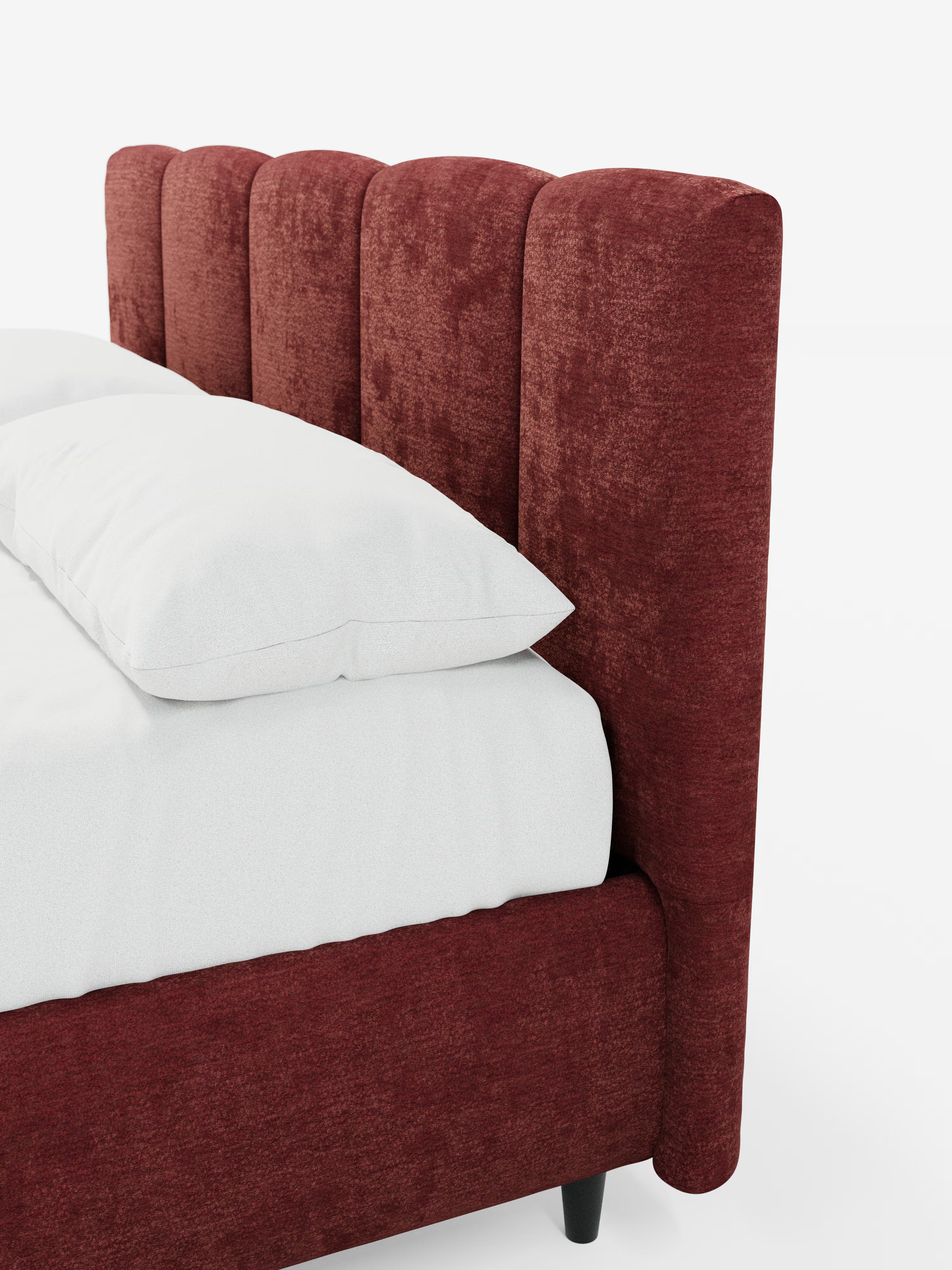 Un primo piano del letto imbottito ARKAM con contenitore e testiera a lavorazione verticale di Letti.store: un letto moderno in stile shabby chic realizzato in tessuto certificato Oeko-Tex®. La testiera, alta e imbottita, presenta pannelli verticali arrotondati di un rosso intenso. Il letto è abbinato a biancheria da letto e cuscini bianchi e gambe nere, il tutto su uno sfondo bianco a tinta unita.