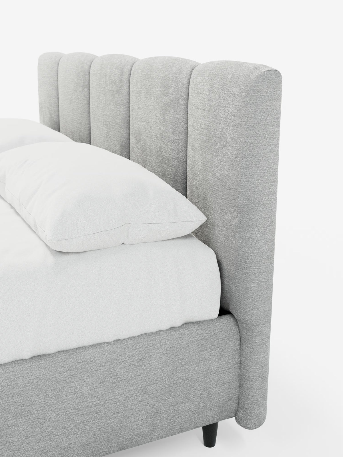 Un primo piano del letto imbottito ARKAM con contenitore e testiera a lavorazione verticale di Letti.store, caratterizzato da una testiera imbottita di colore grigio chiaro con scanalature verticali e da una struttura coordinata. Il letto è abbellito da biancheria da letto bianca, tra cui un morbido cuscino e un piumone. Questo elegante letto imbottito in tessuto certificato Oeko-Tex® poggia su corte gambe nere su uno sfondo bianco a tinta unita, mettendo in risalto il suo design shabby chic.