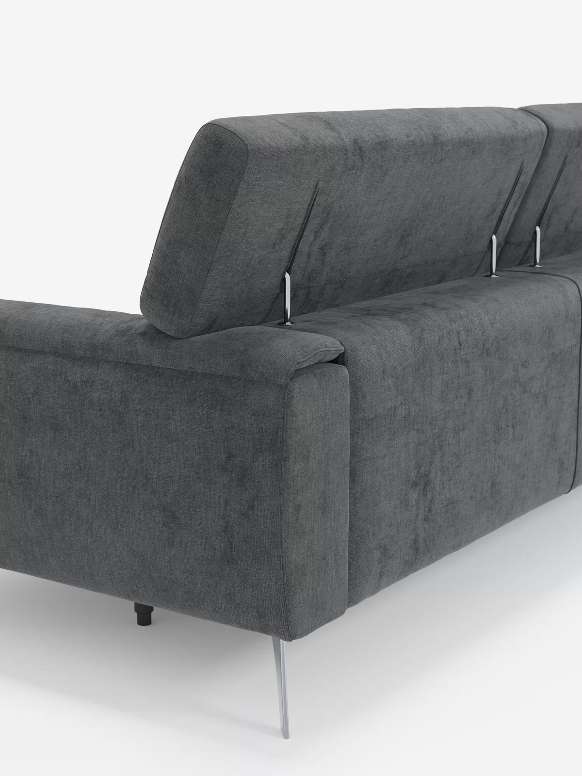 Il divano Caravaggio 2 e 3 posti di Divani.Store, in grigio scuro e in stile contemporaneo, è raffigurato di retro, con gambe angolate in metallo e poggiatesta reclinabili sostenuti da sottili aste metalliche. Rivestito con l'elegante tessuto T31, facile da pulire e dalla morbida finitura simile al velluto, questo divano include anche sedute allungabili per un comfort ancora maggiore. Lo sfondo è bianco a tinta unita.