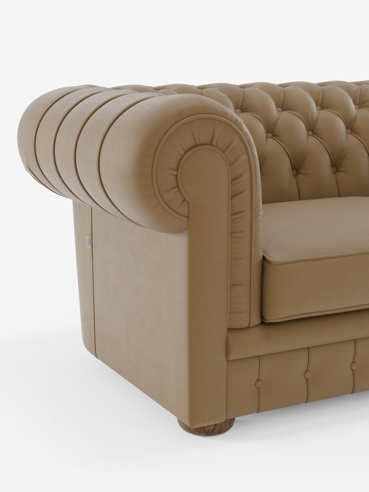 Primo piano del bracciolo destro del modello Chester – Divano Chesterfield in vera pelle spessorata a 2 e 3 posti di Divani.Store. Il bracciolo in pelle color cuoio presenta un bordo arrotondato e una profonda trapuntatura, in armonia con il classico schienale trapuntato. Questo divano Chesterfield presenta piedini in legno e un cuscino di seduta liscio, che risalta su uno sfondo bianco a tinta unita.