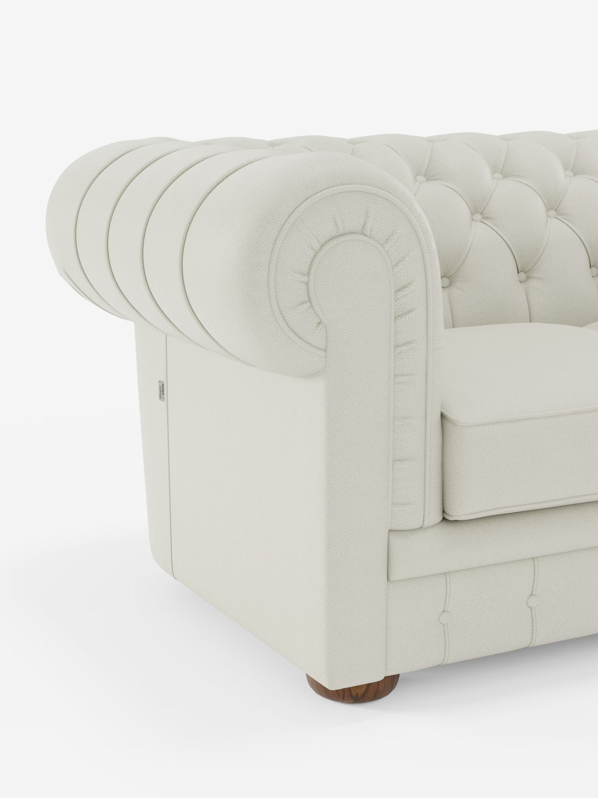Primo piano del bracciolo del divano “Chester 4 Posti 3 sedute in Vera Pelle – Chesterfield Capitonné Artigianale” di Divani.Store, caratterizzato da un rivestimento in vera pelle color crema con finitura testurizzata, capitonné profondo, bracciolo arrotondato e piedini in legno. Realizzato in Italia, il design classico ed elegante del divano risalta sullo sfondo bianco a tinta unita.