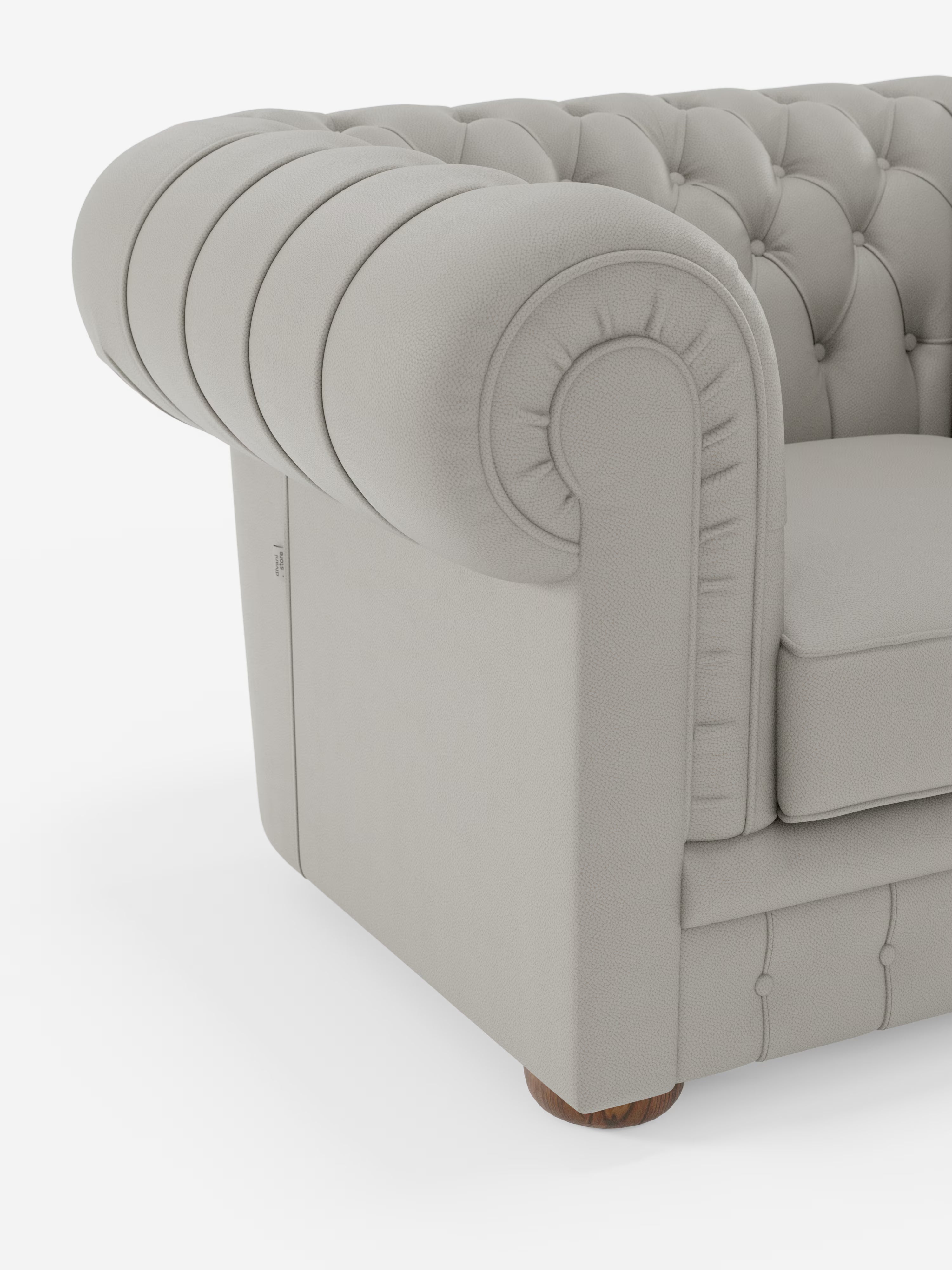 Primo piano del bracciolo sinistro e della seduta della poltrona Chester in vera pelle spessorata con capitonné artigianale di Divani.Store. Questa poltrona in stile Chesterfield color grigio chiaro presenta braccioli elegantemente arrotondati, dettagli artigianali con bottoni che richiamano la lavorazione capitonné, un morbido cuscino, un raffinato rivestimento in vera pelle e poggia su una gamba corta e rotonda in legno.