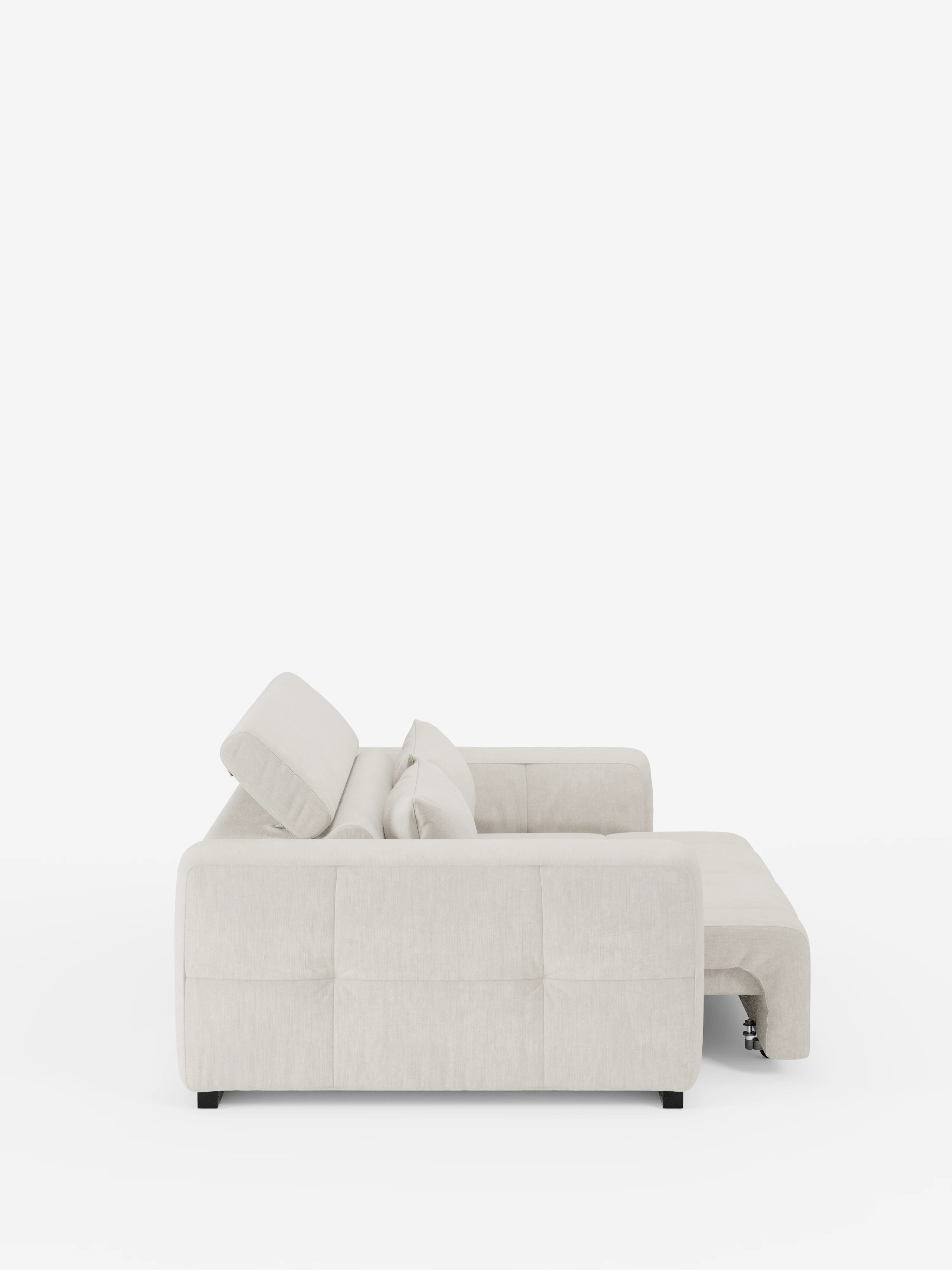 Vista laterale del divano Monarch con relax elettrico per l’allungamento delle sedute e poggiatesta reclinabile di Divani.Store, un moderno divano componibile in beige chiaro, rivestito in morbido tessuto T31 resistente alle macchie. Caratterizzato da ampi braccioli e cuscini trapuntati, questo design minimalista e contemporaneo è raffigurato su uno sfondo bianco a tinta unita con la chaise longue che si estende verso destra. Non sono visibili altri oggetti.
