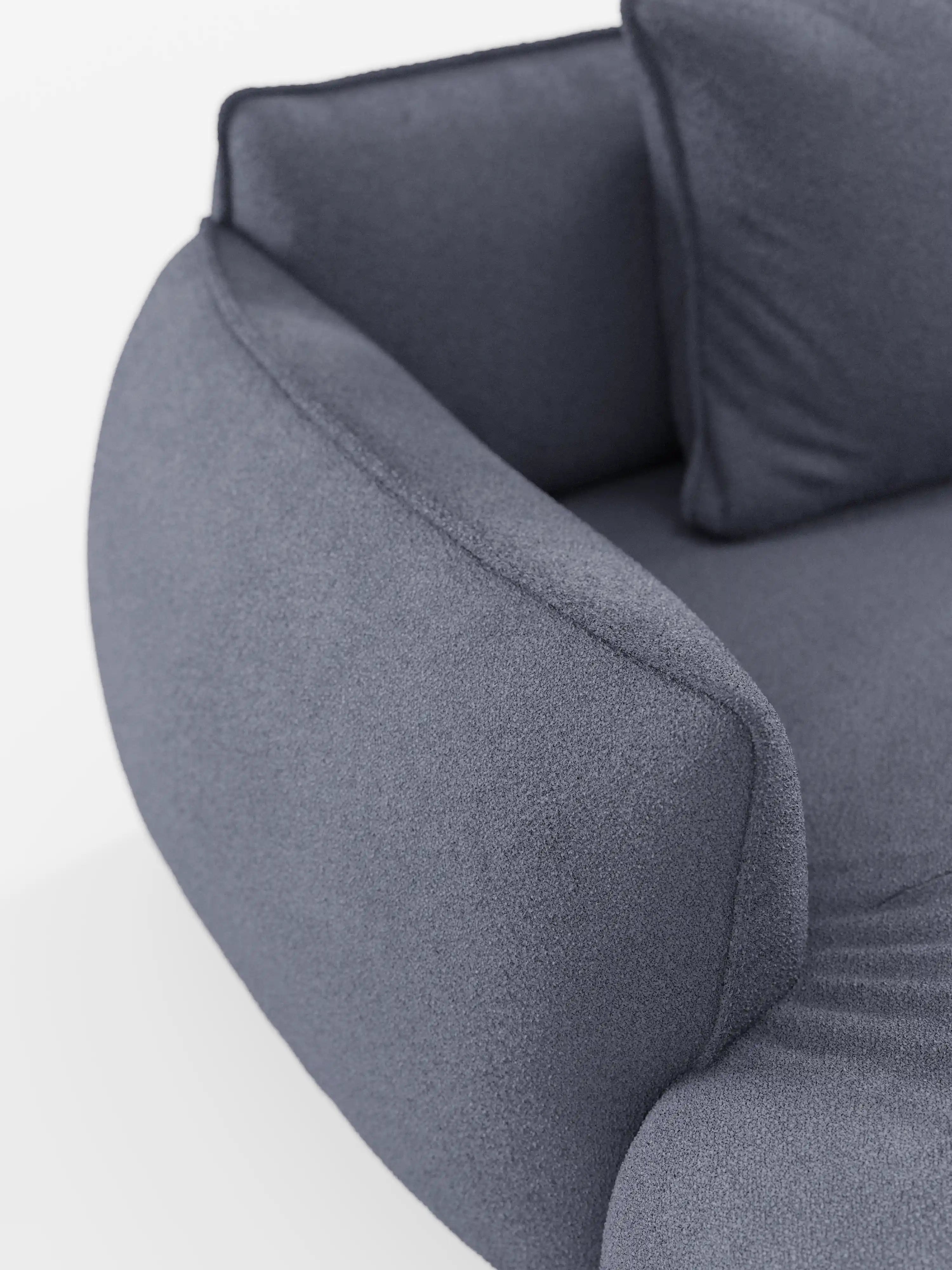 Primo piano del divano angolare panoramico componibile Nimbus con penisola e angolo in tessuto smacchiabile T33 di Divani.Store — un moderno divano imbottito grigio dalle linee curve, progettato in Italia — che mette in risalto i suoi morbidi braccioli, lo schienale arrotondato, un cuscino coordinato e il tessuto testurizzato antimacchia su uno sfondo bianco. Sono visibili solo una parte della seduta e del cuscino.