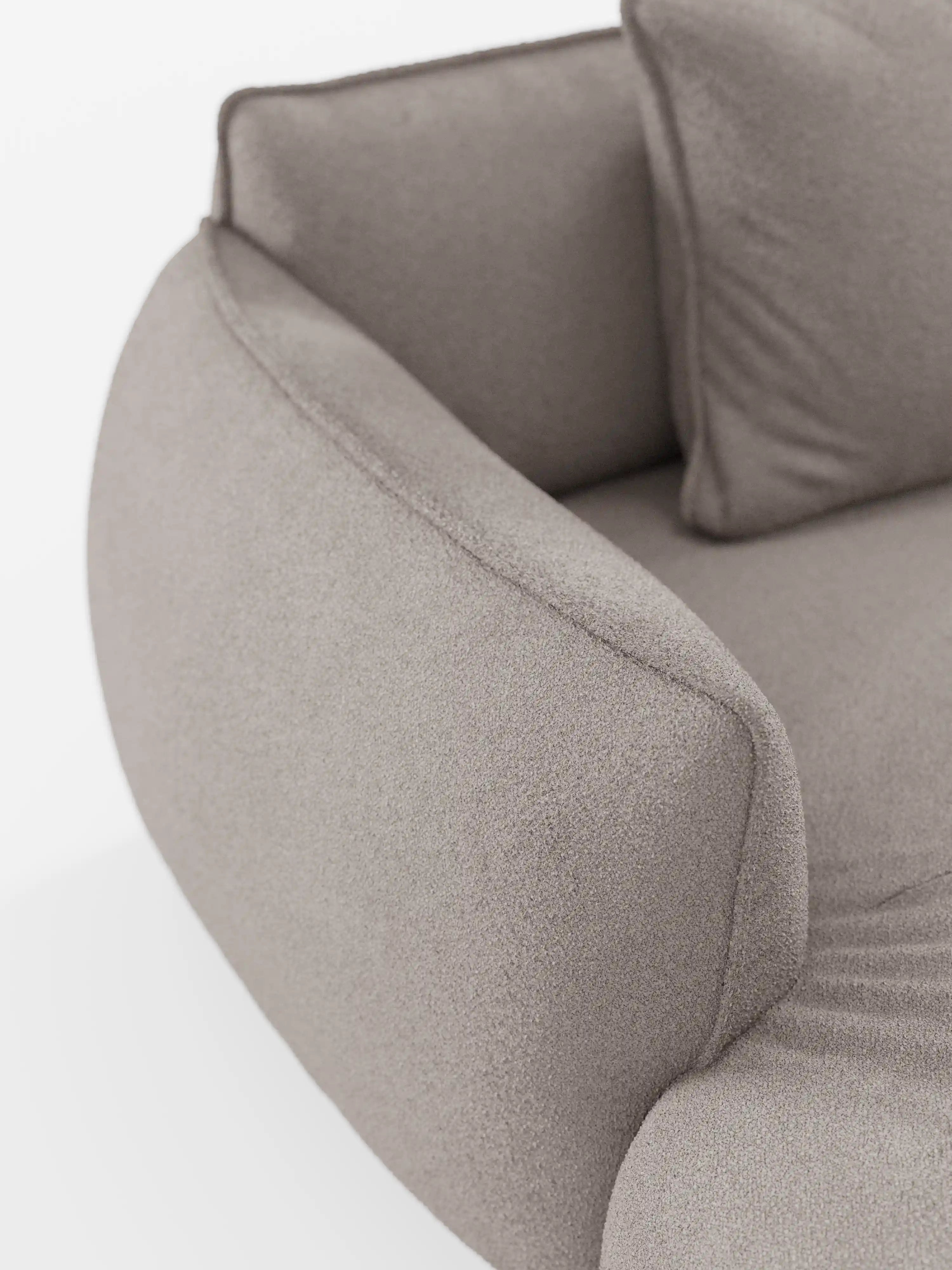 Primo piano del divano angolare panoramico componibile Nimbus con penisola e angolo in tessuto smacchiabile T33 di Divani.Store, caratterizzato da un rivestimento moderno in grigio chiaro con braccioli morbidi e sinuosi e un soffice cuscino coordinato. La superficie liscia ma leggermente ruvida del tessuto conferisce un aspetto accogliente e invitante. Questo elegante divano sfoderabile incarna la migliore tradizione del design Made in Italy. Lo sfondo è luminoso e minimalista.
