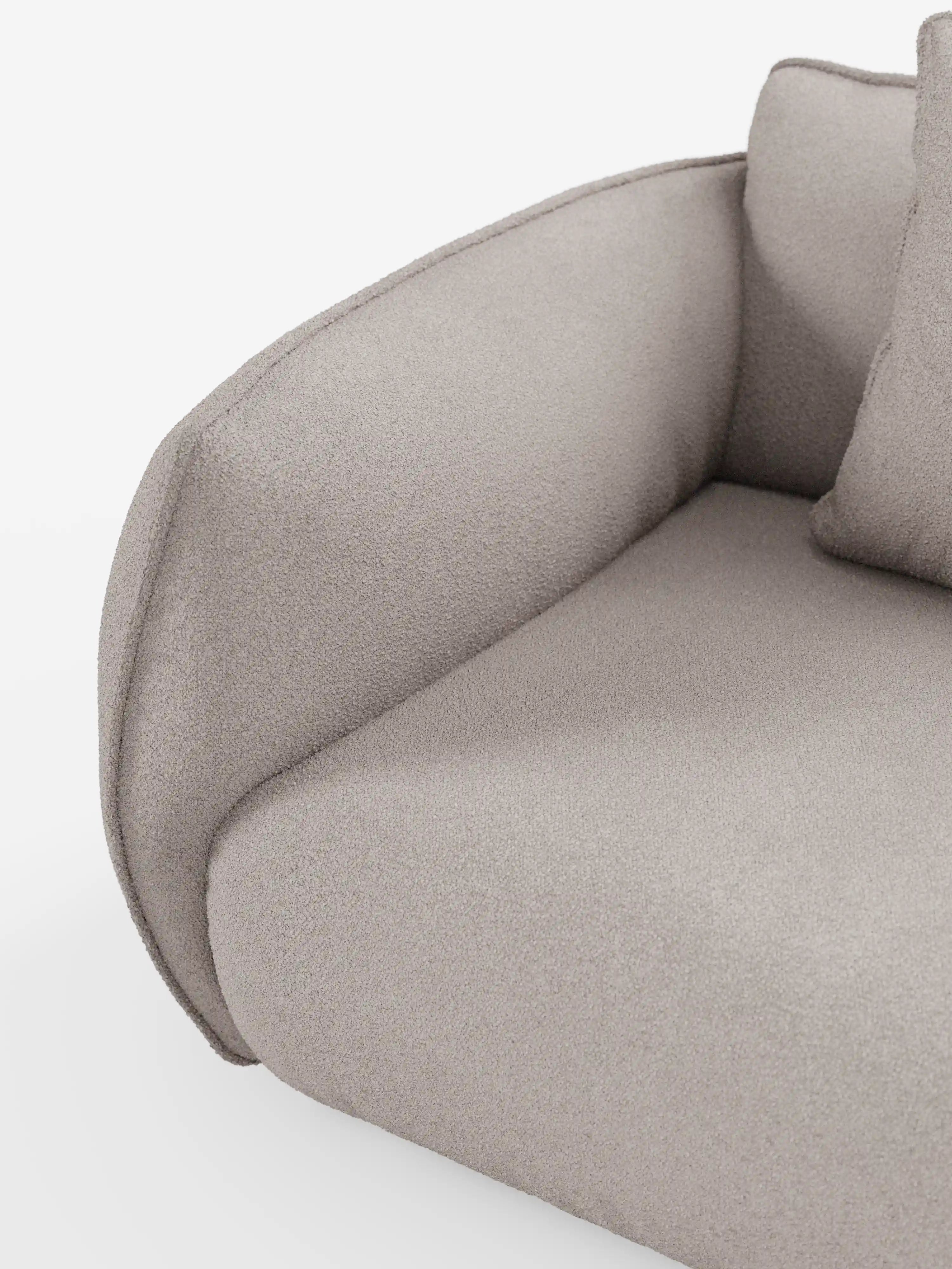 Primo piano del divano angolare con penisola componibile Nimbus di Divani.Store, in tessuto T33 grigio chiaro effetto cotone, antimacchia. L’immagine mette in risalto il bracciolo curvo e una sezione della seduta, esaltando il rivestimento morbido e dalla trama ricca. Su uno sfondo bianco è parzialmente visibile un cuscino coordinato, senza altri oggetti presenti.