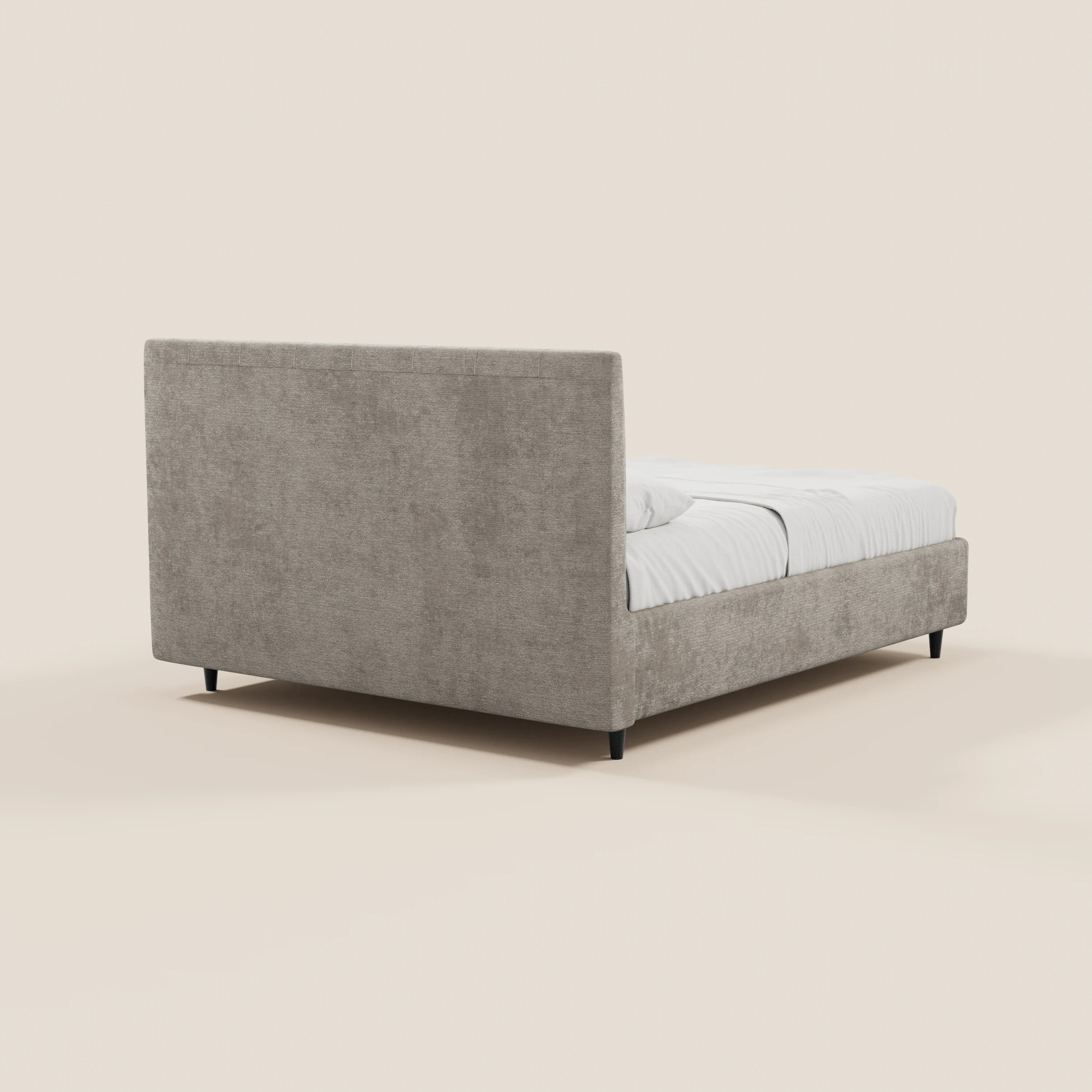 Un moderno letto imbottito ONYX con contenitore di Letti.store, caratterizzato da un'alta testiera verticale in tessuto certificato Oeko-Tex® color beige chiaro, è raffigurato in una prospettiva laterale posteriore con biancheria da letto bianca su uno sfondo bianco sporco.